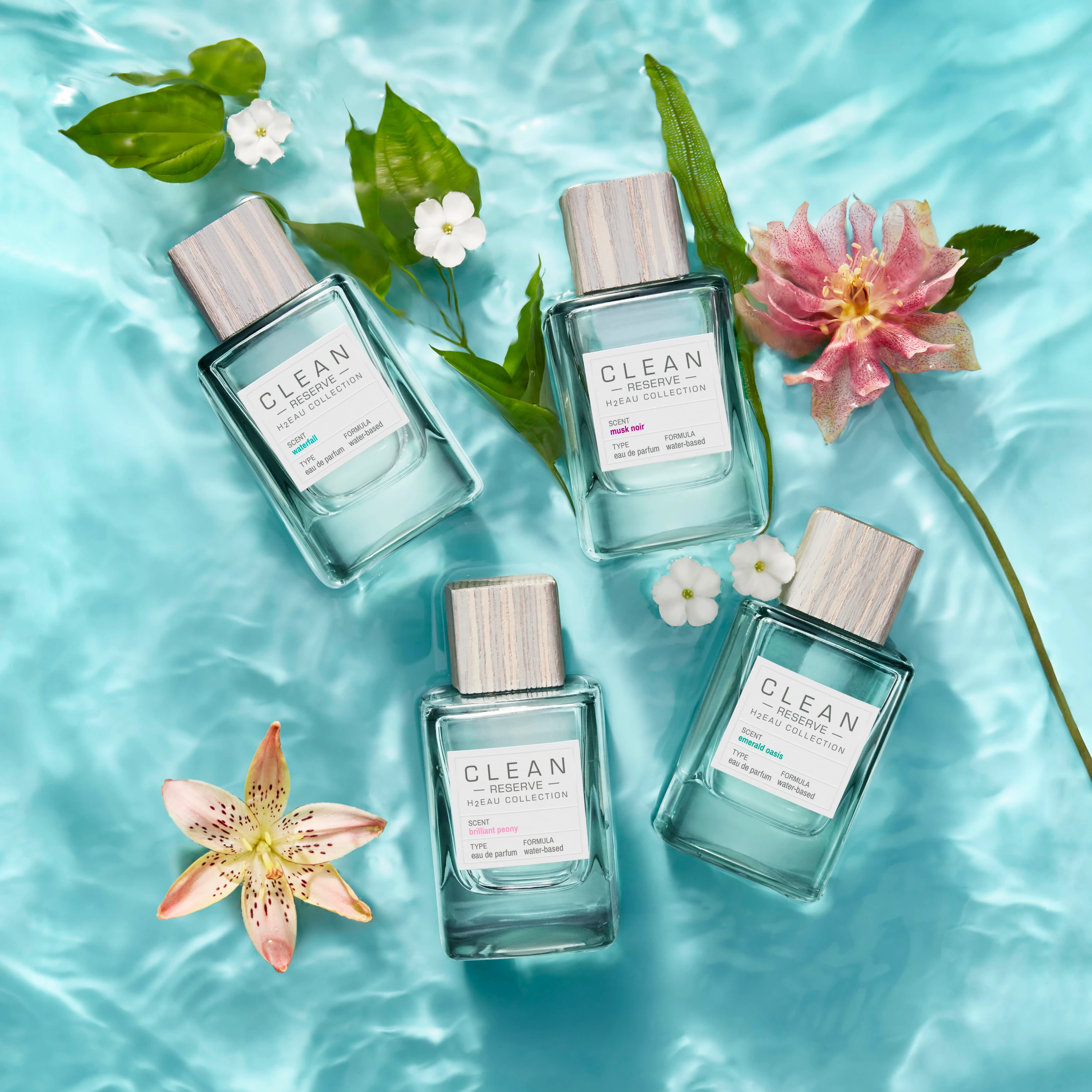 Four Clean Reserve bottles and flowers floating on aqua water.