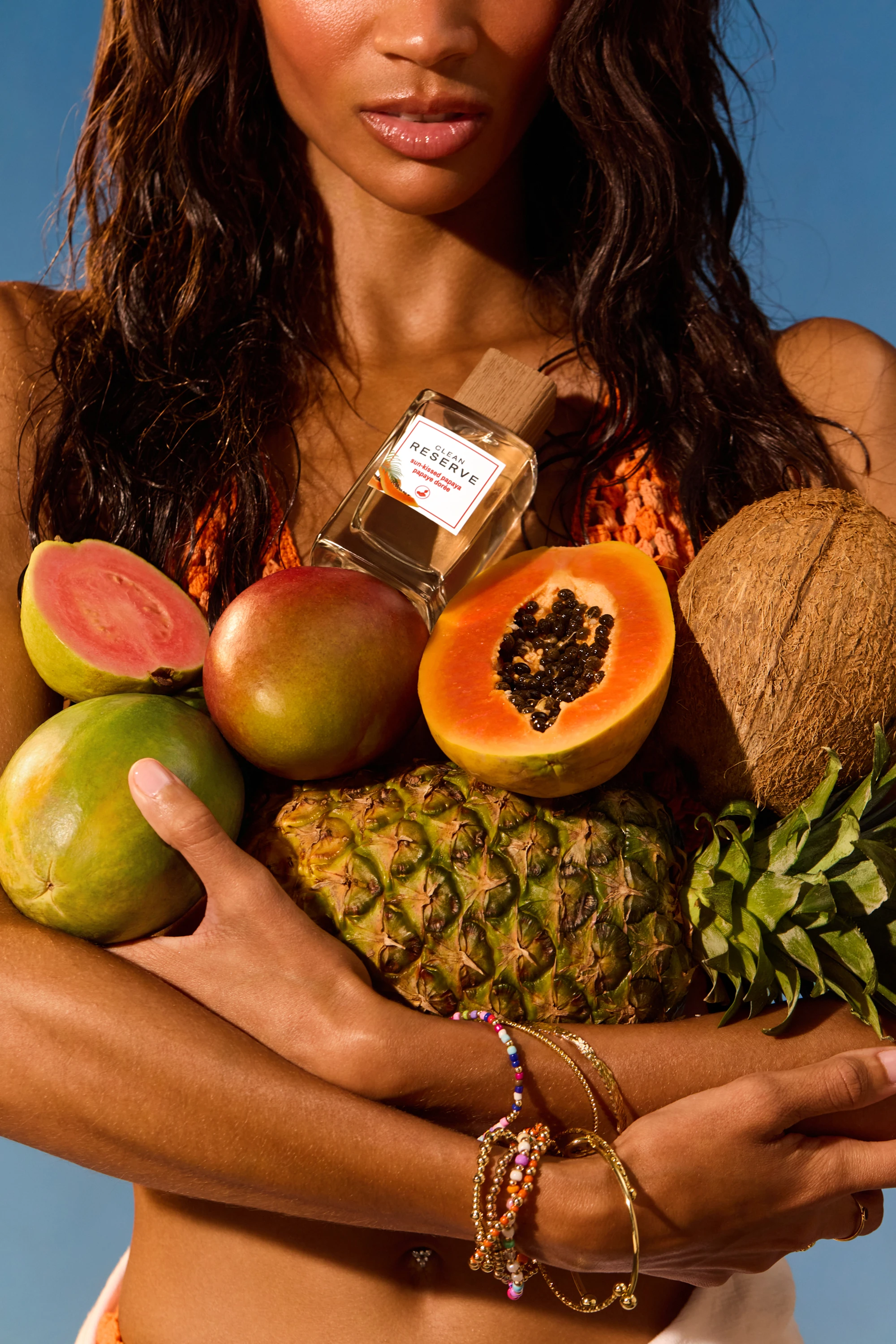 A model holding tropical fruit and a Clean Reserve bottle.
