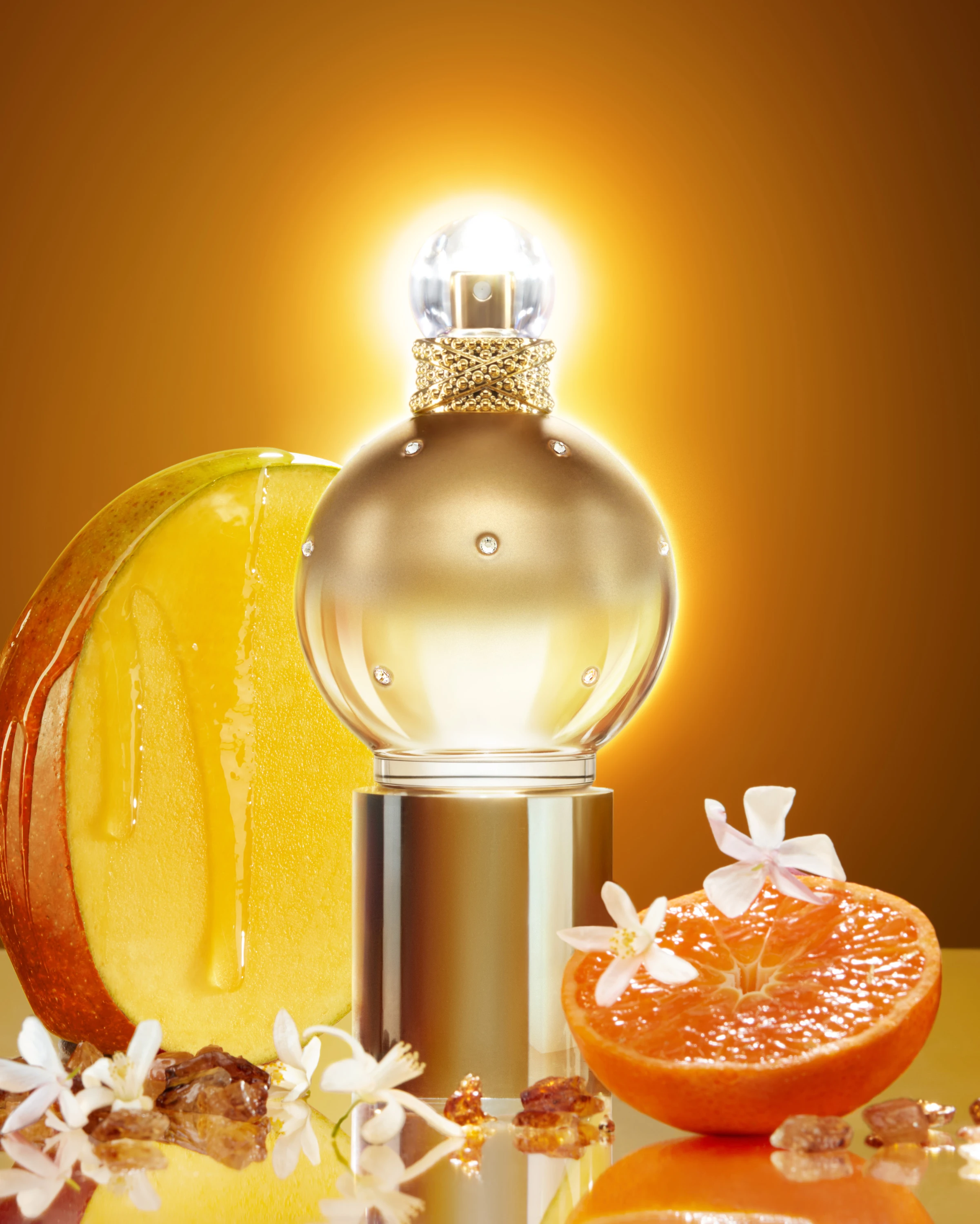 A gold fragrance bottle with orange slices.