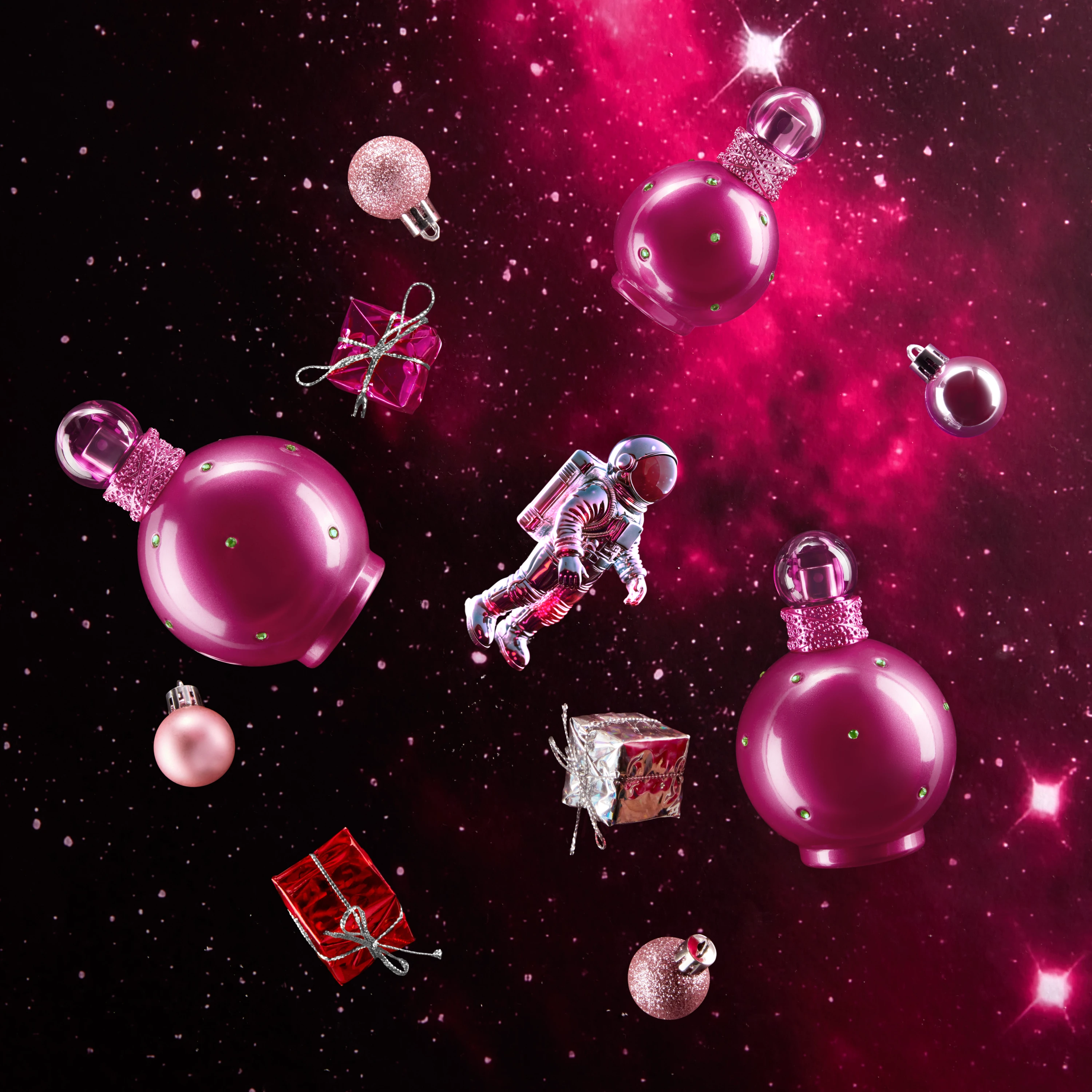Pink fragrance bottles and decorative objects against a sparkling background.