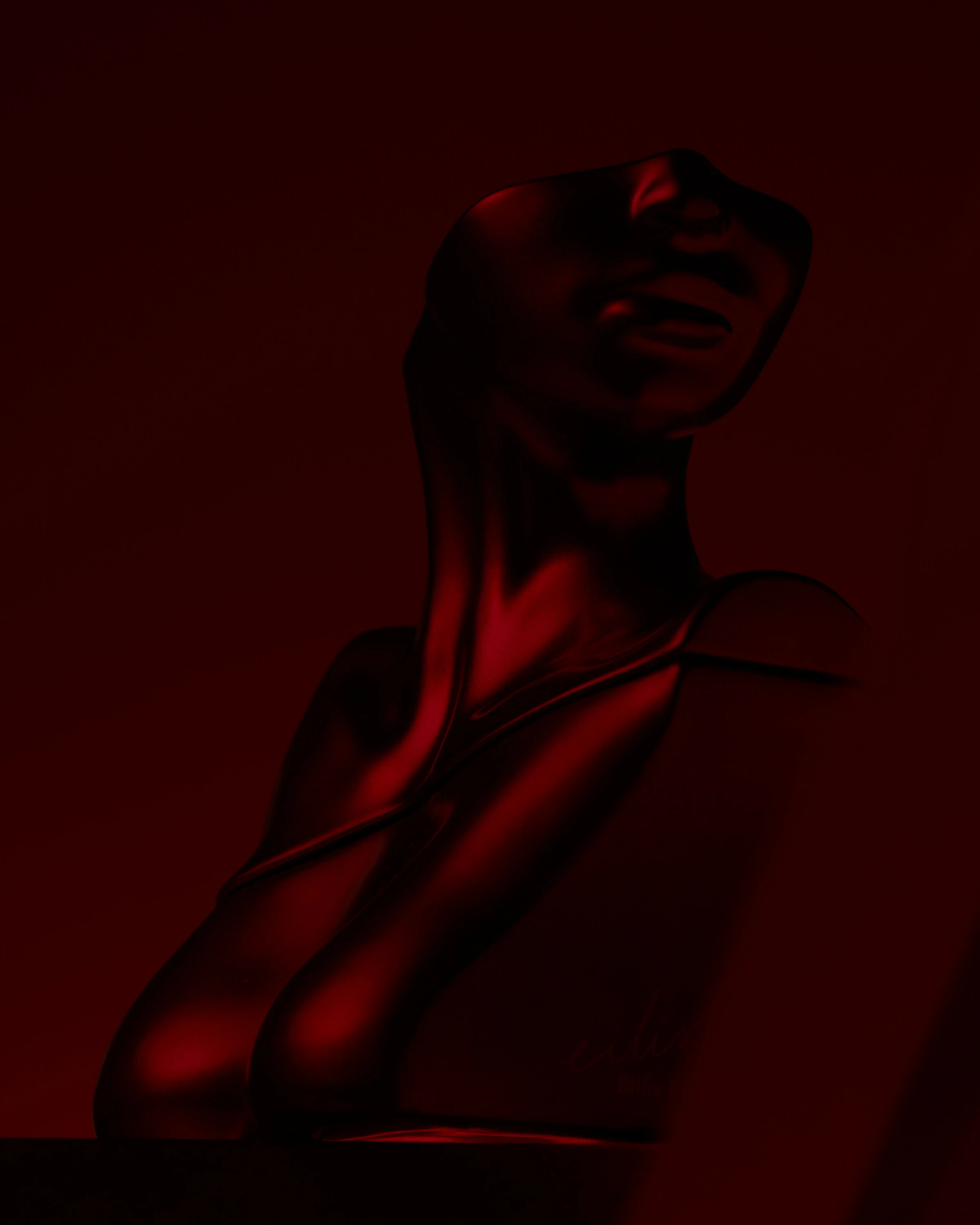 A red sculptural Billie Eilish bottle in low light.