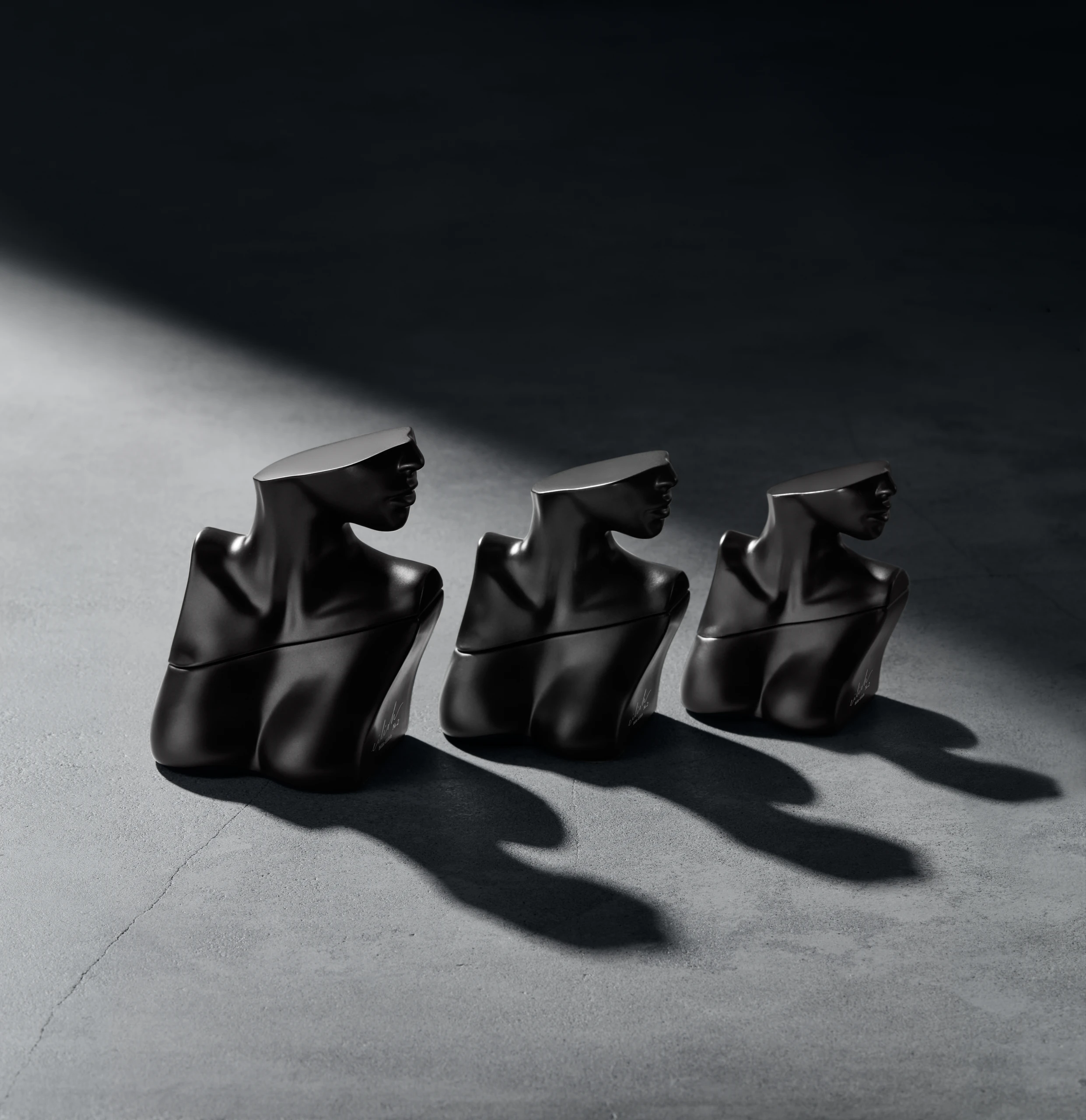 Three dark sculptural Billie Eilish fragrance bottles.