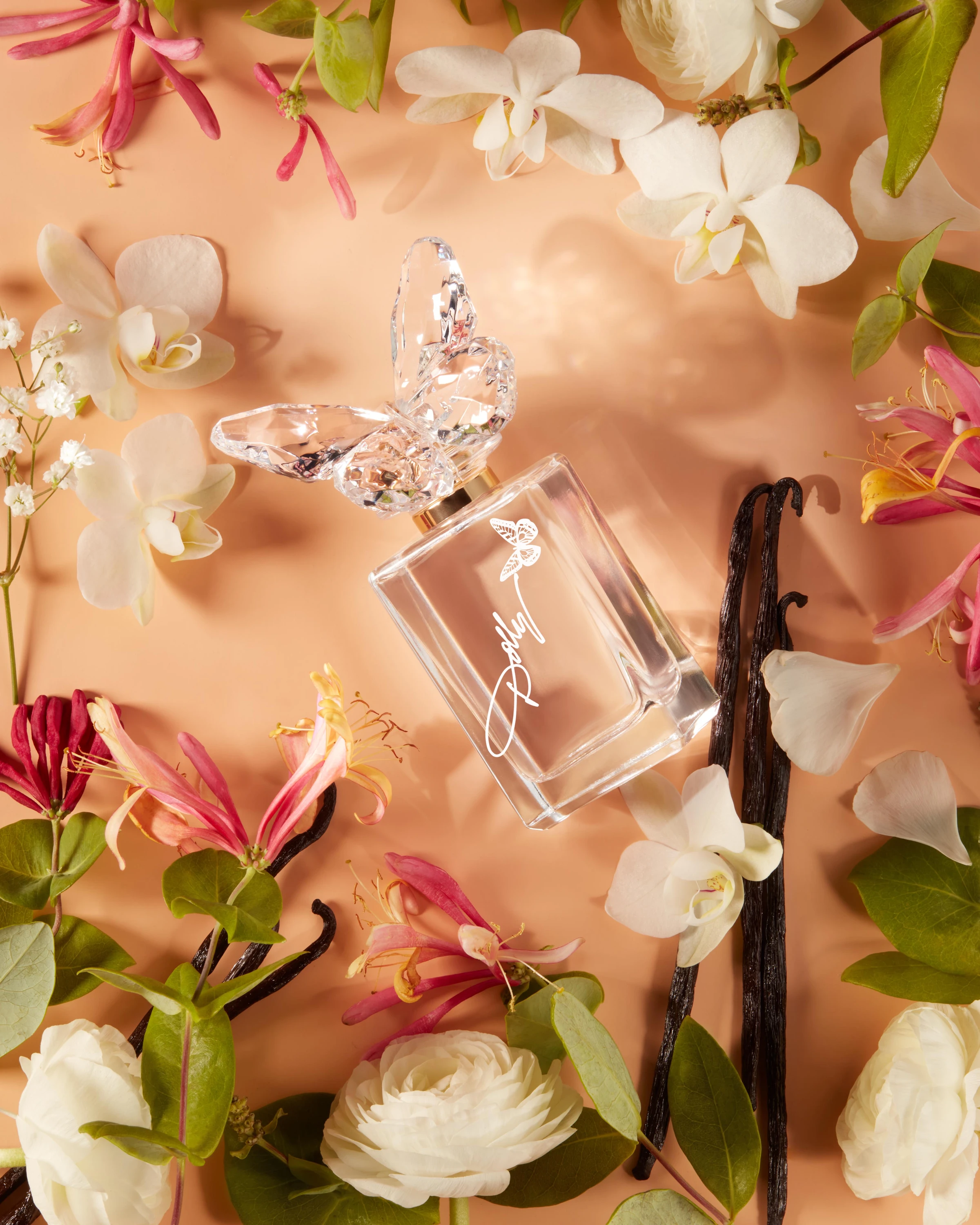 A Dolly Parton fragrance bottle surrounded by flowers and vanilla pods.