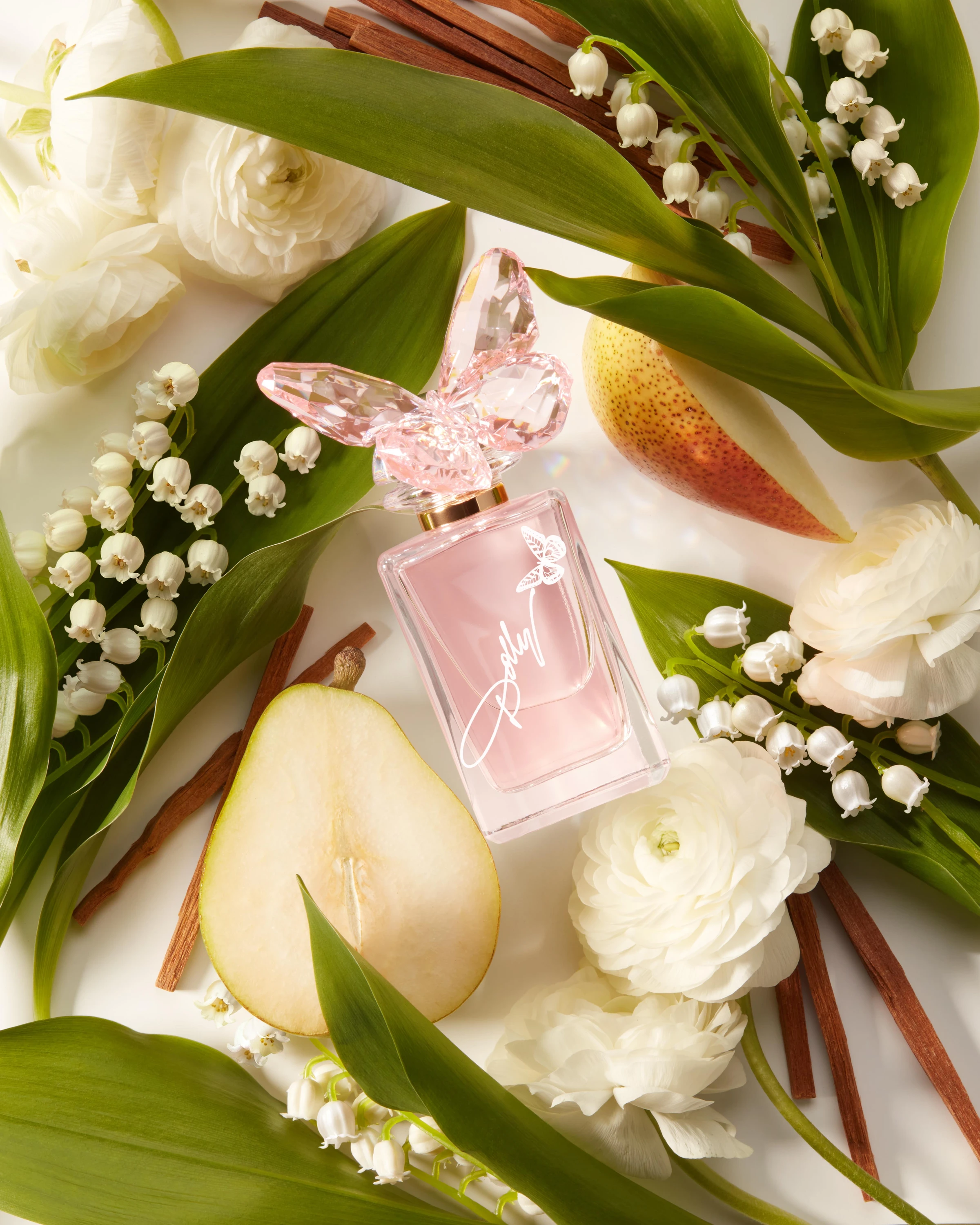 A pink Dolly Parton bottle among pale flowers and green leaves.