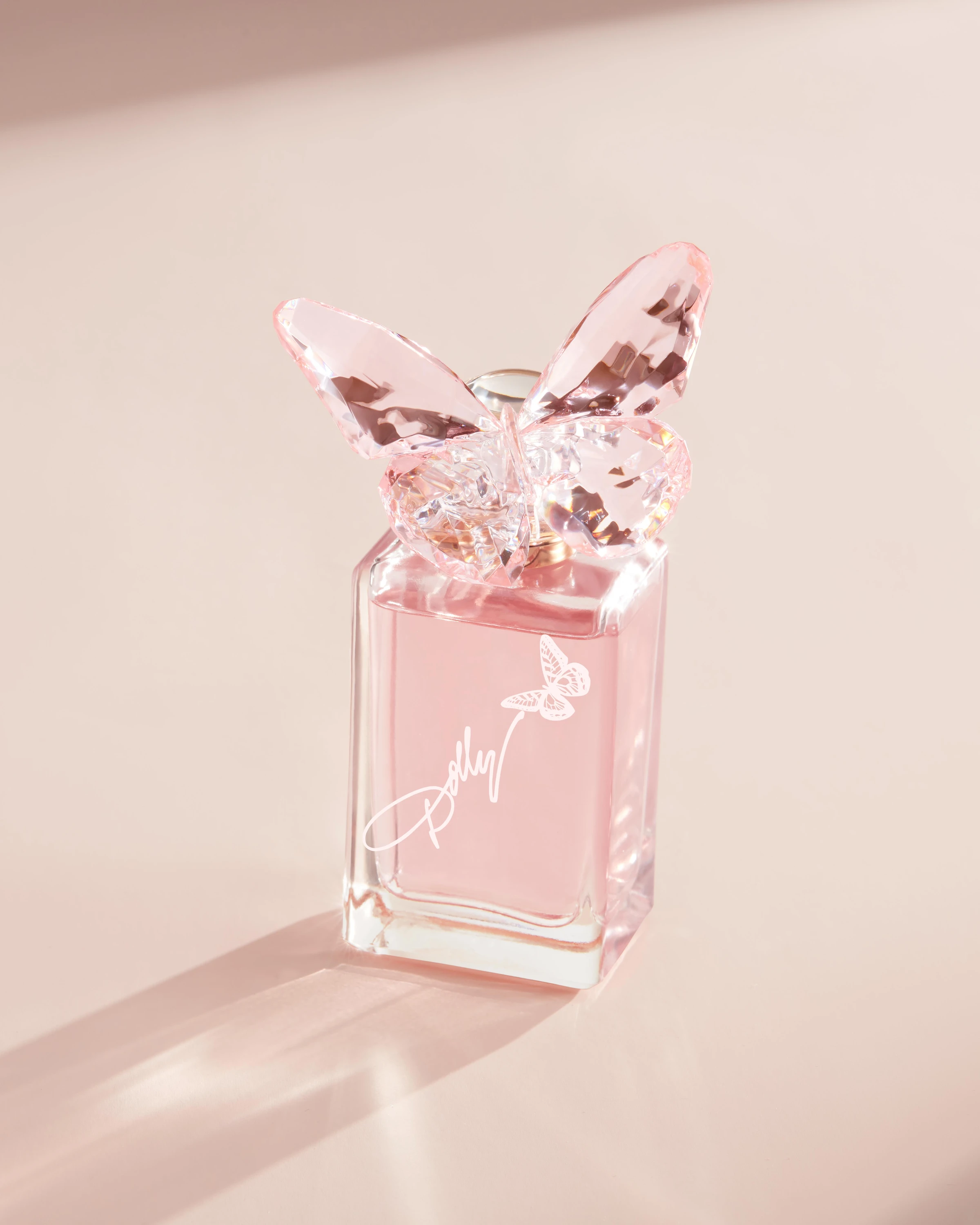 A pink Dolly Parton fragrance bottle with a butterfly-shaped cap.