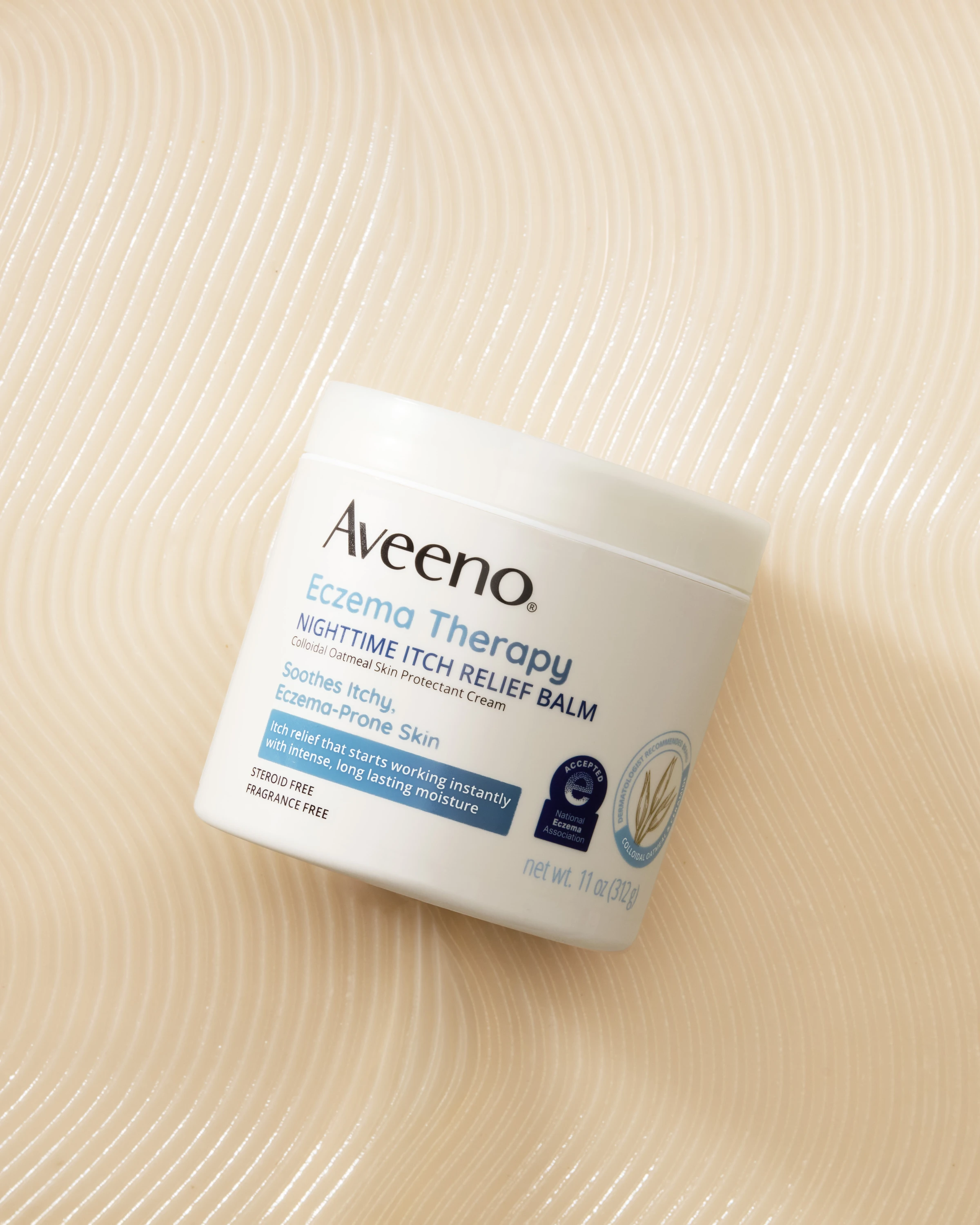 An Aveeno jar resting on textured pale fabric.