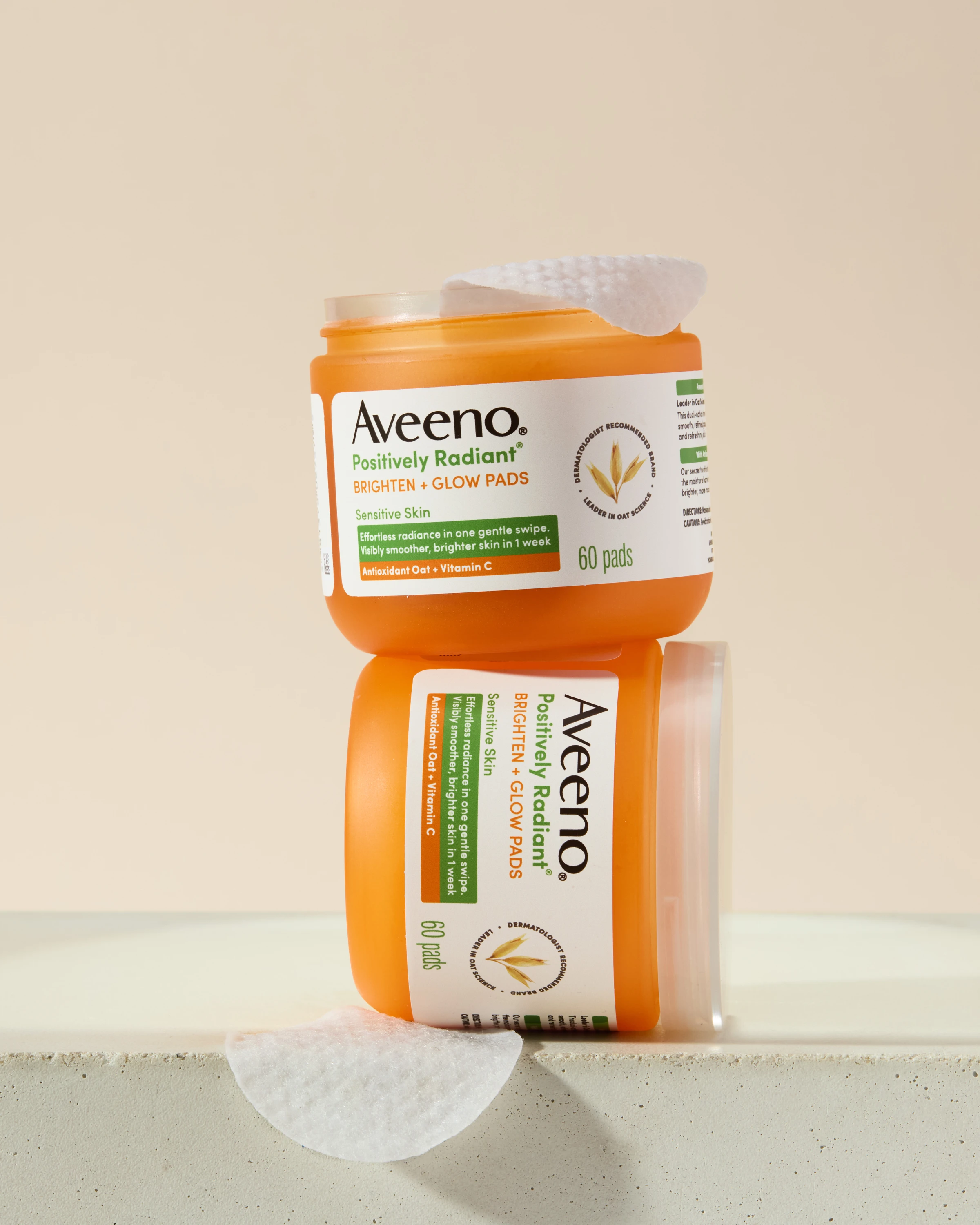 Two Aveeno jars stacked against a pale background.