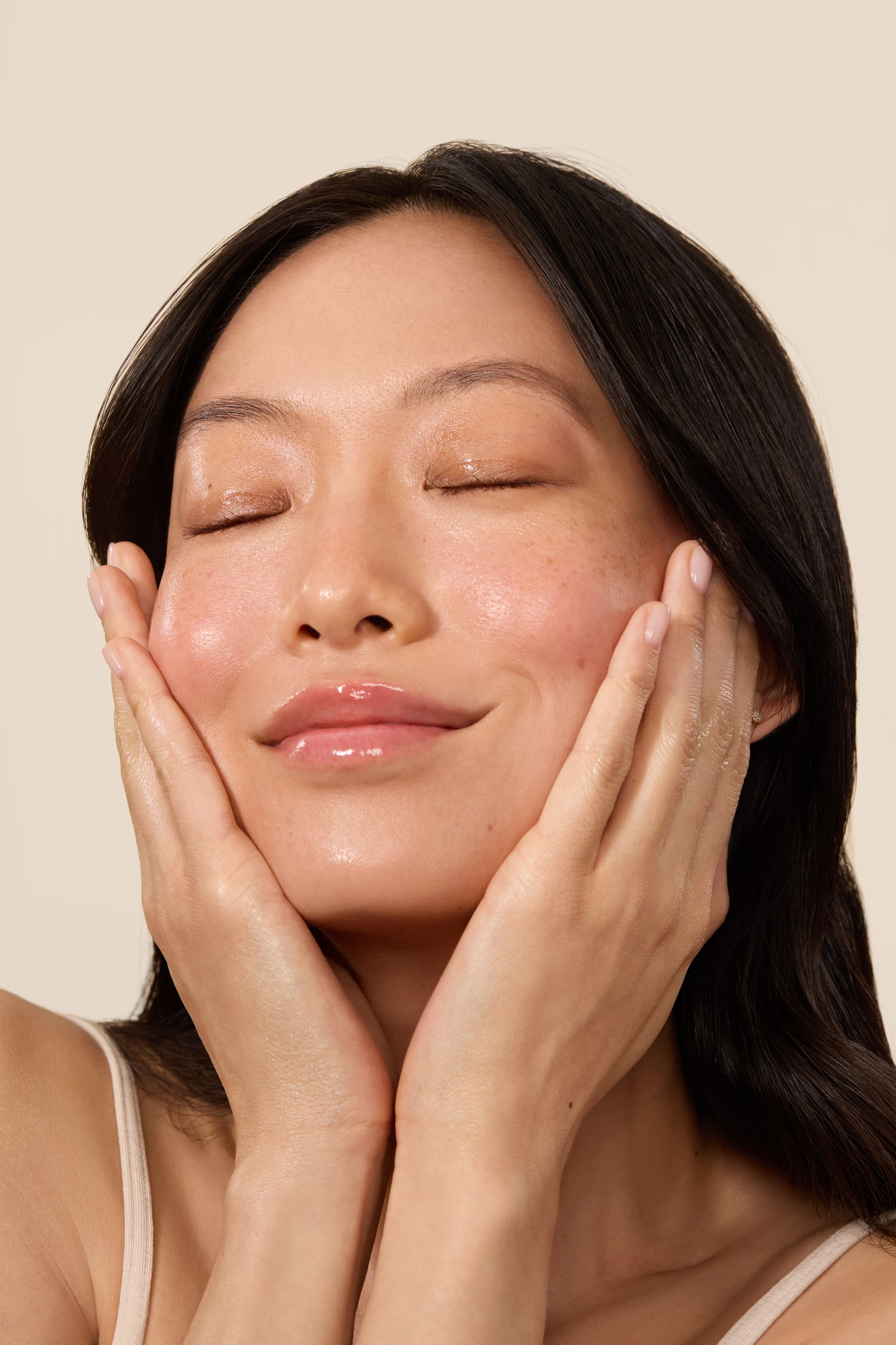 A model gently pressing both hands to her cheeks.