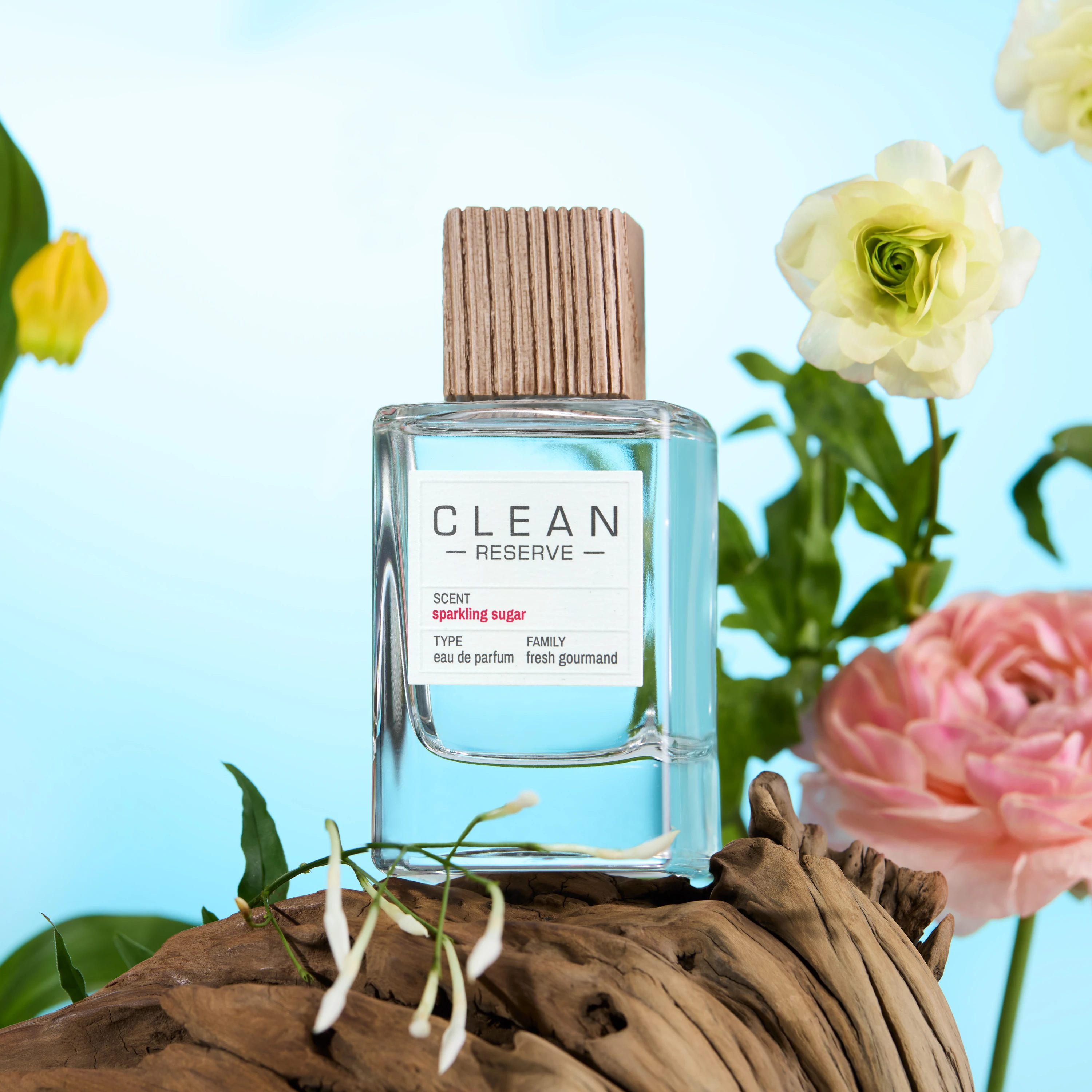 A Clean Reserve bottle on wood beside pink and pale flowers.