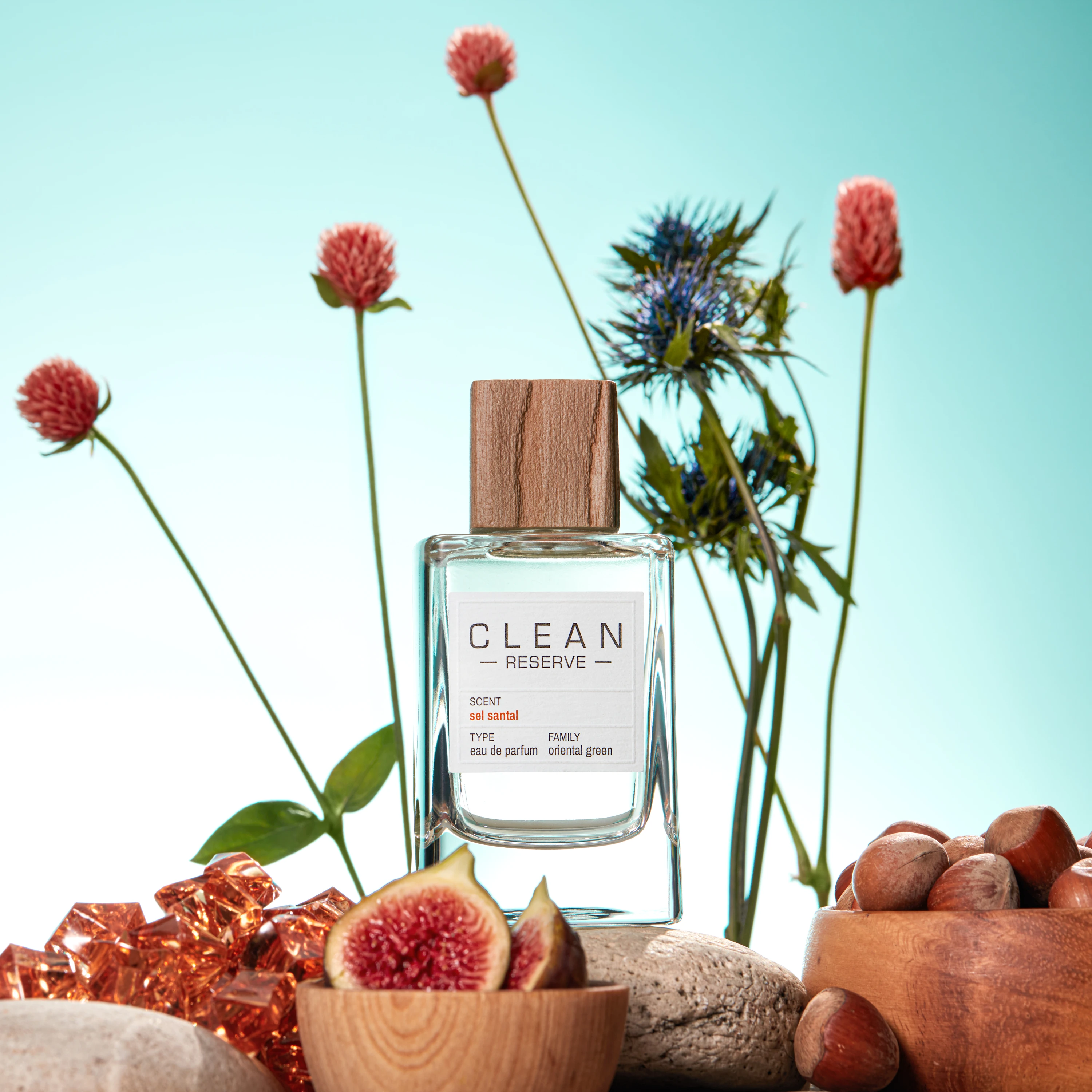 A Clean Reserve bottle surrounded by fruit and tall flowers.