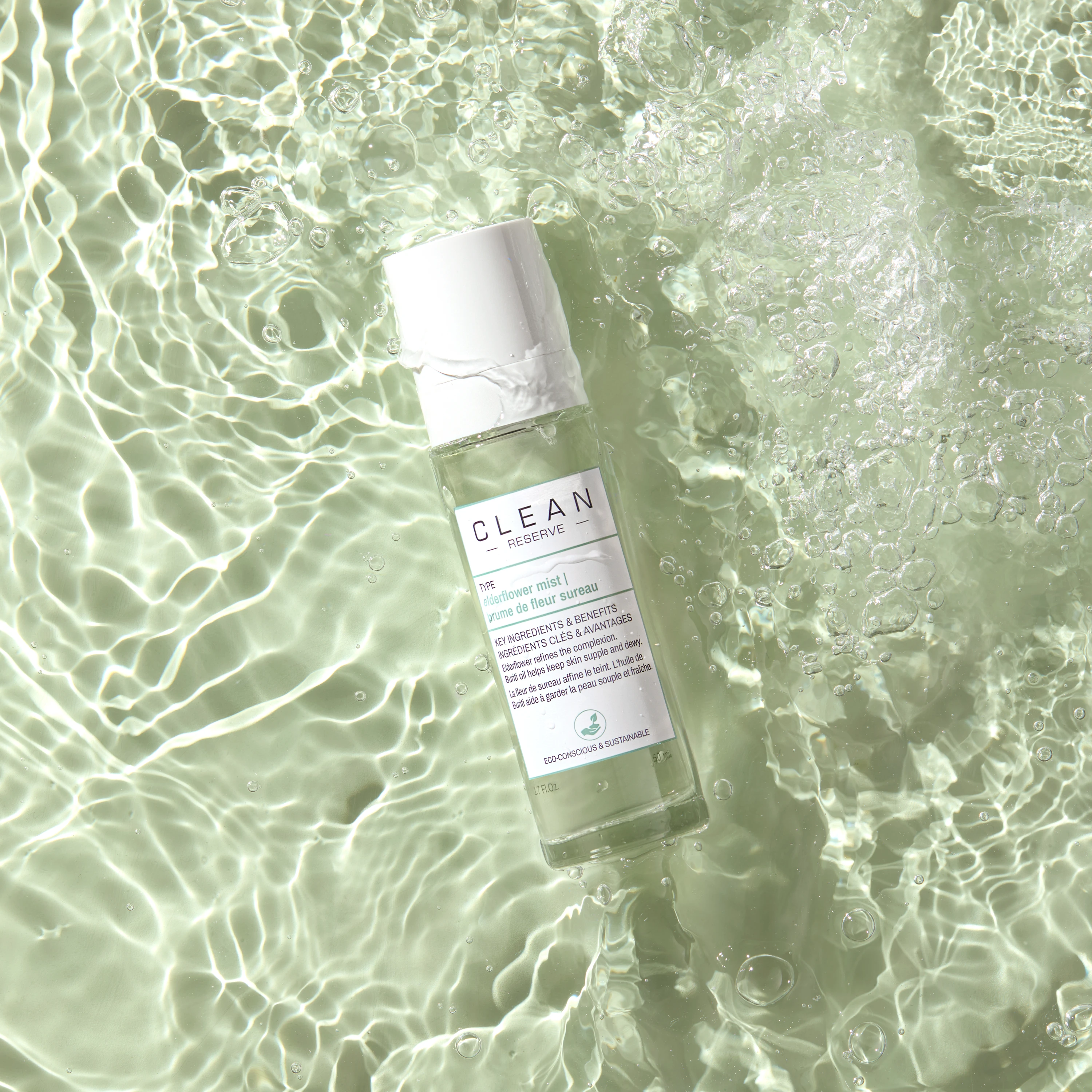 A white fragrance spray bottle resting in shallow water.