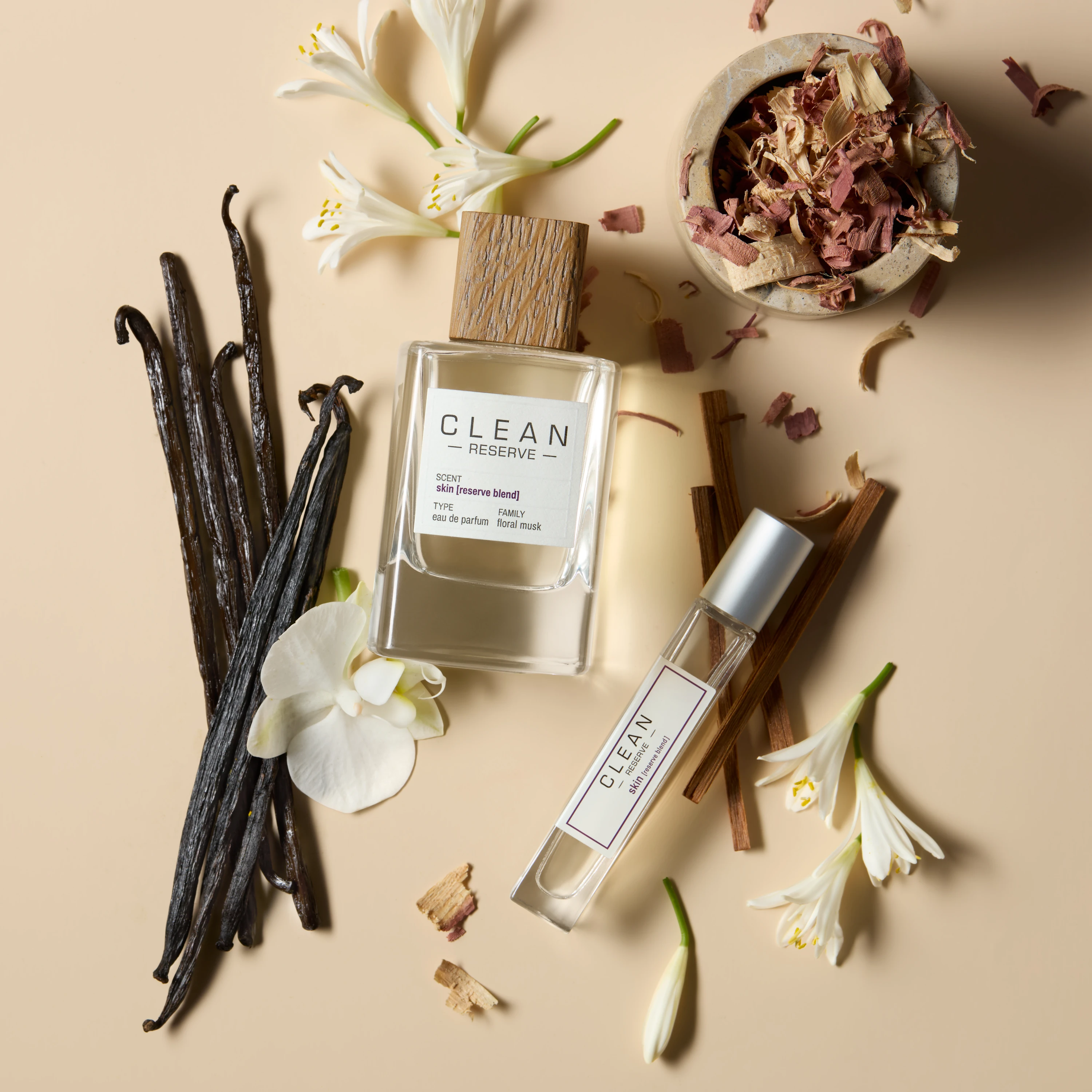 Clean Reserve bottle and travel spray surrounded by flowers and vanilla pods.