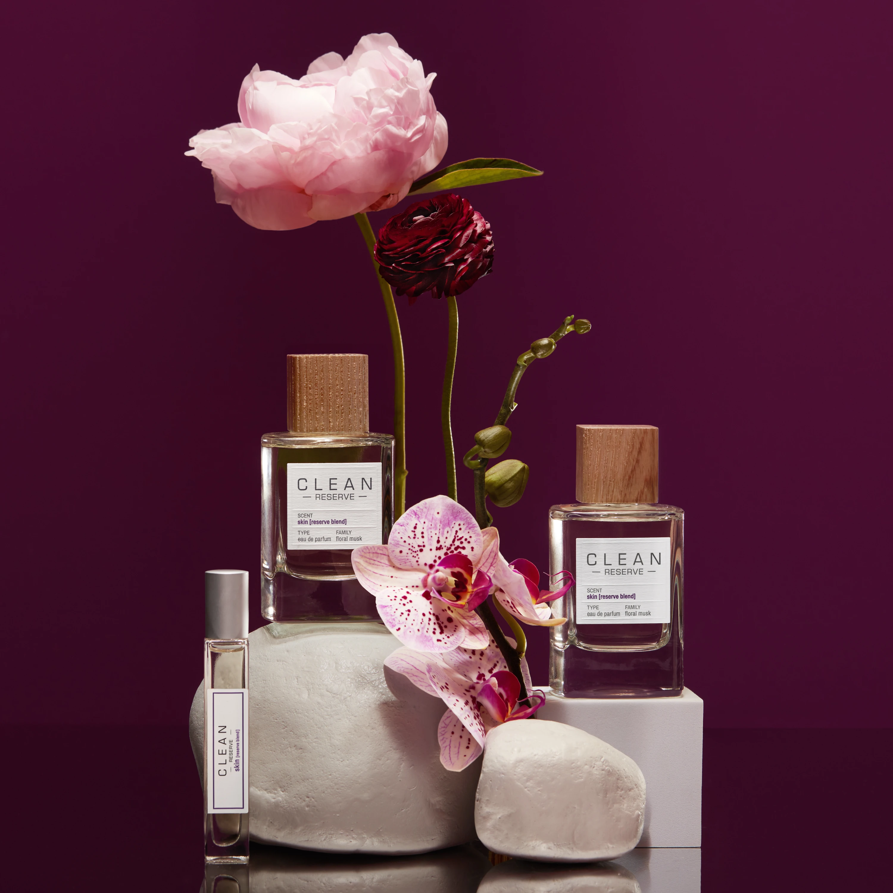 Three Clean Reserve bottles beside pink flowers.