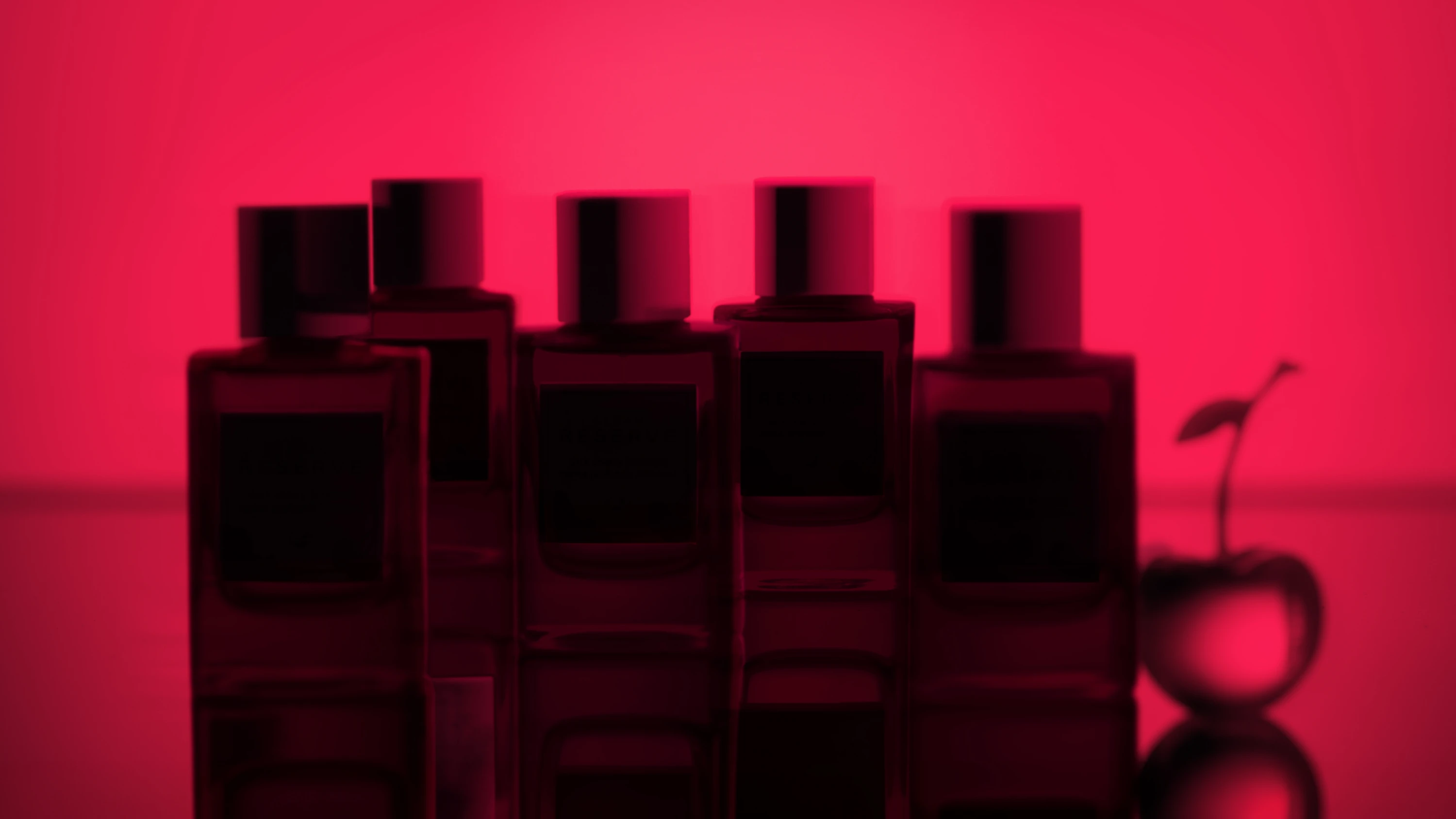 Dark fragrance-bottle silhouettes against a red background.