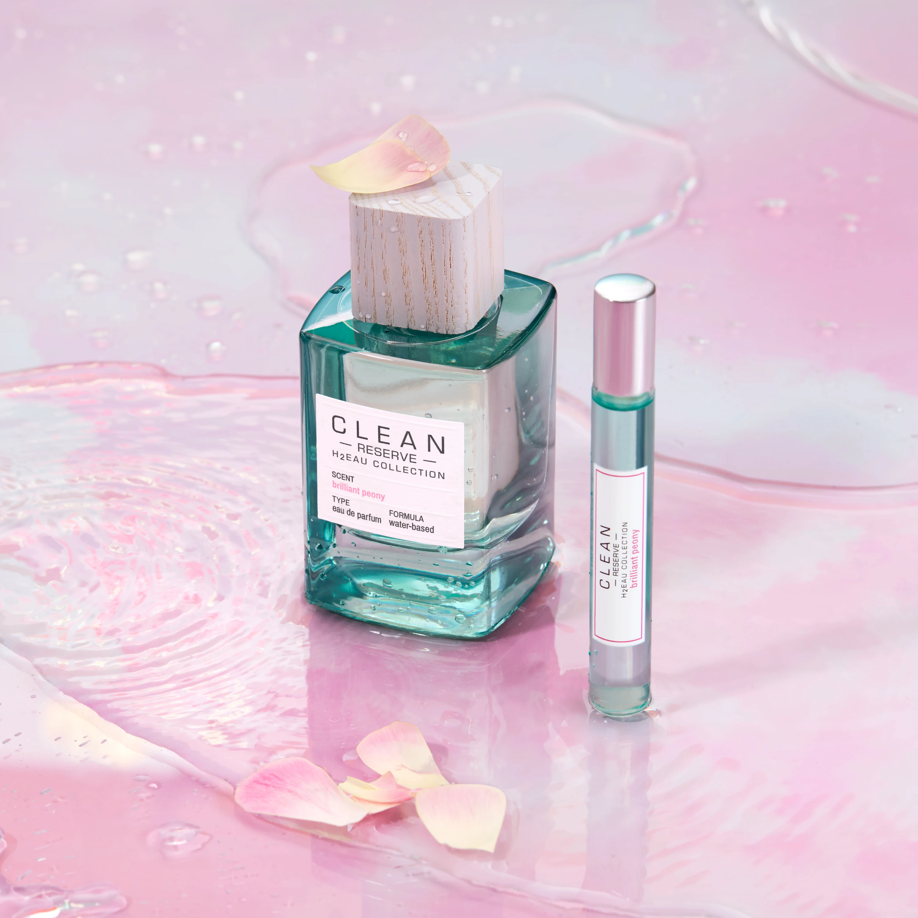Clean Reserve bottle and travel spray on a pink surface.