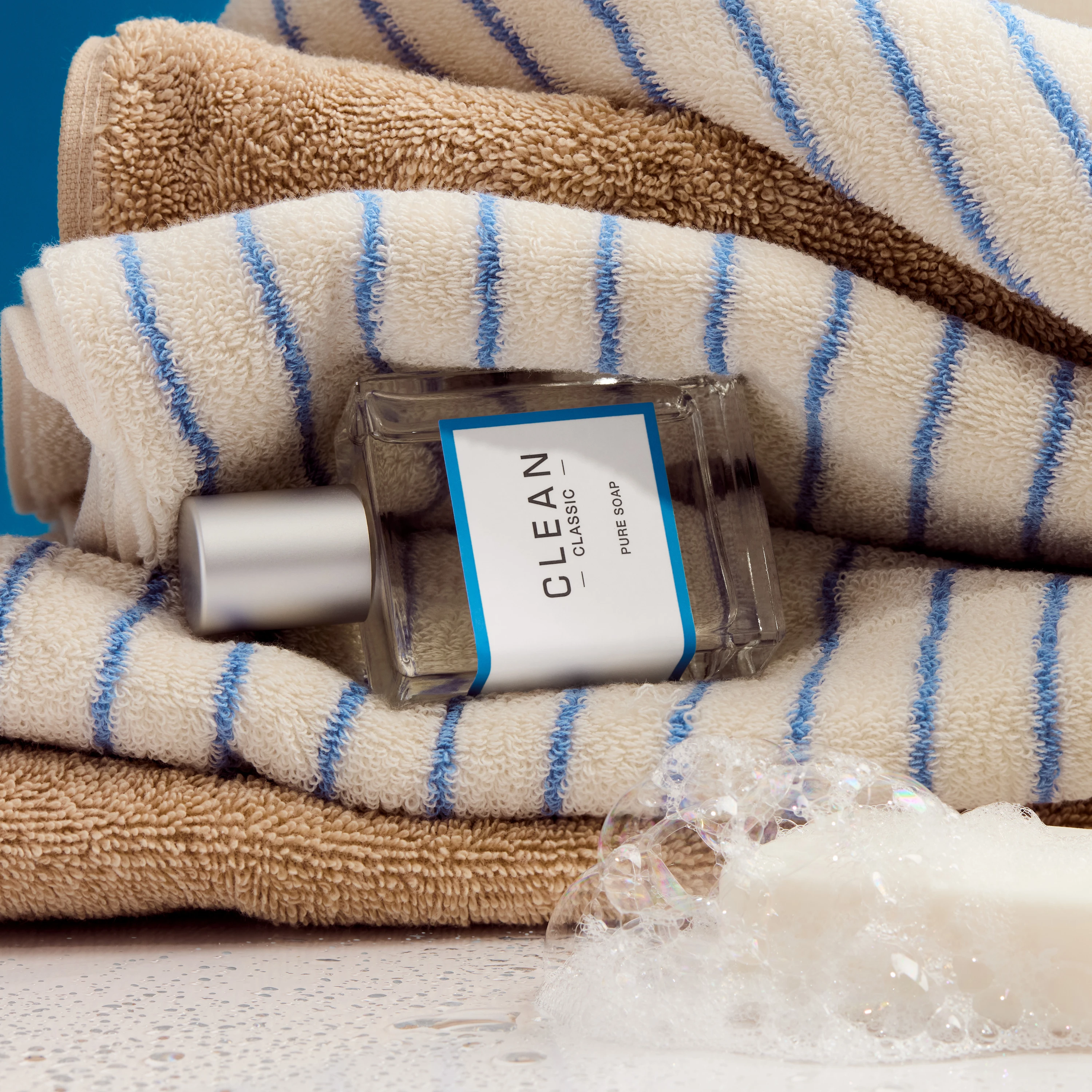 A Clean fragrance bottle on folded striped fabric.