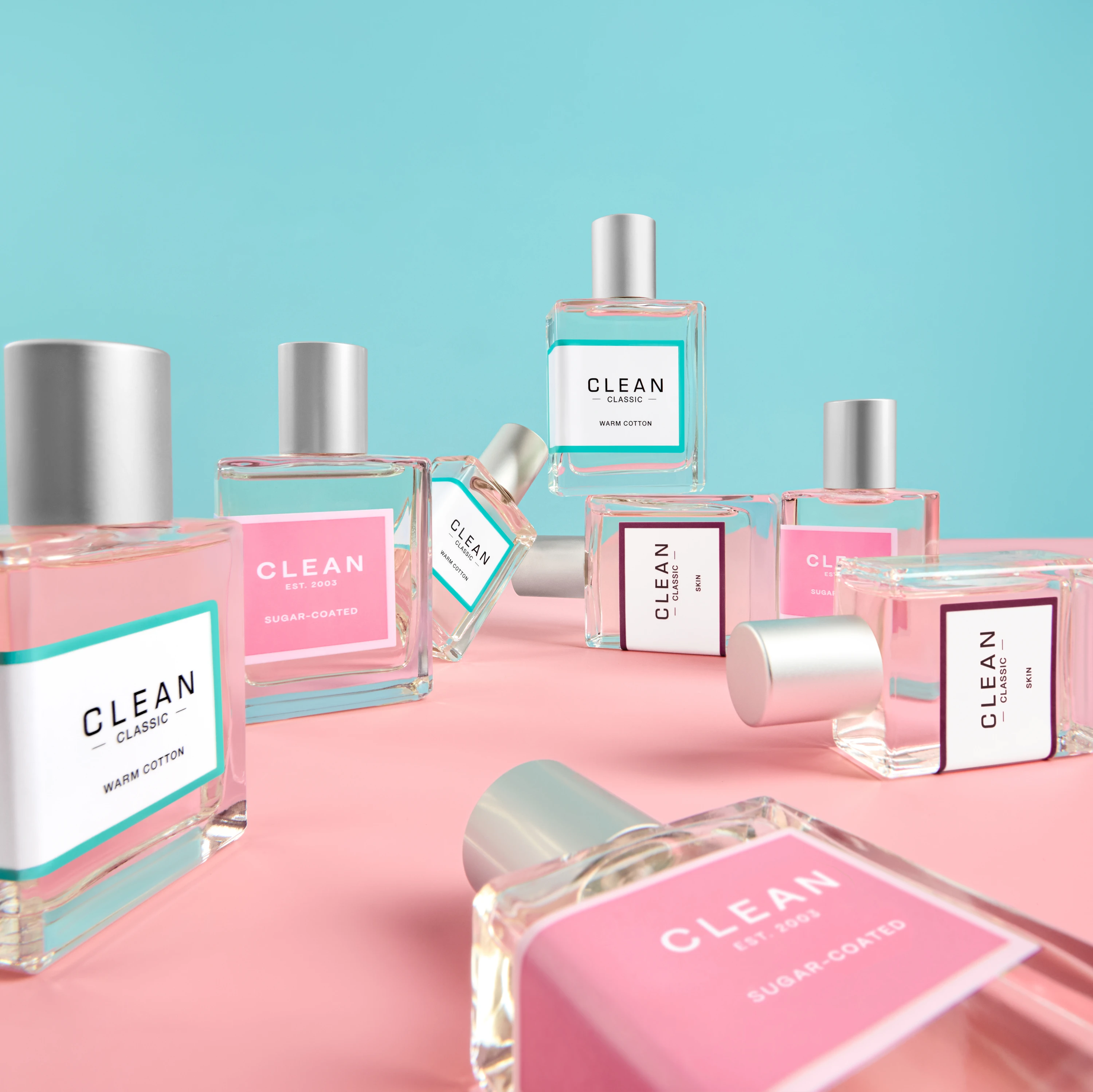 Clean fragrance bottles arranged on pink-and-blue blocks.