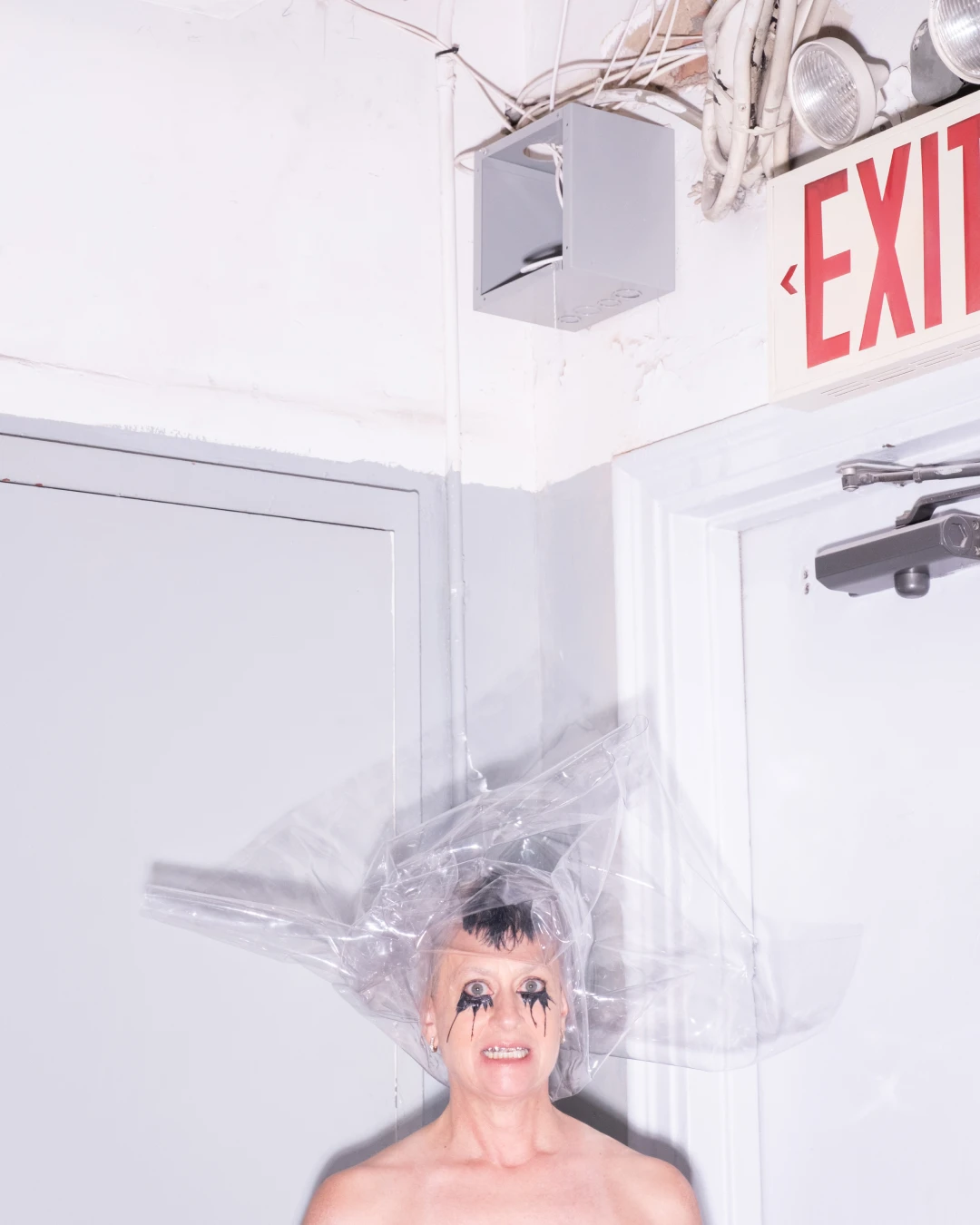 Peaches posing beneath an exit sign in an editorial layout.