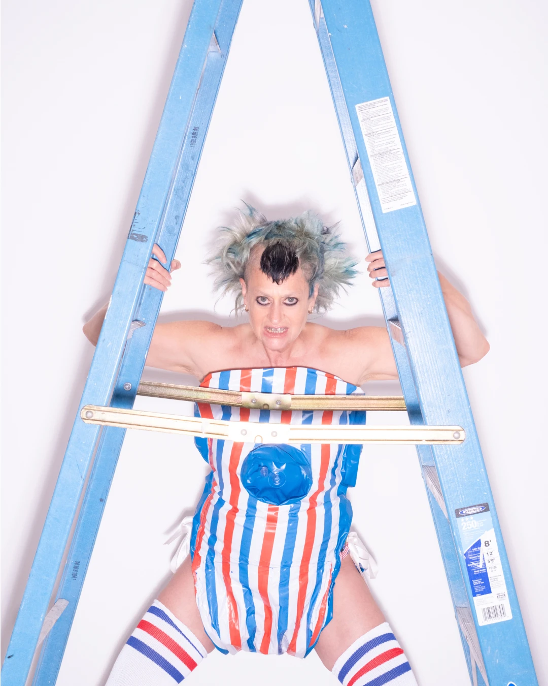 Peaches posing behind a blue ladder.