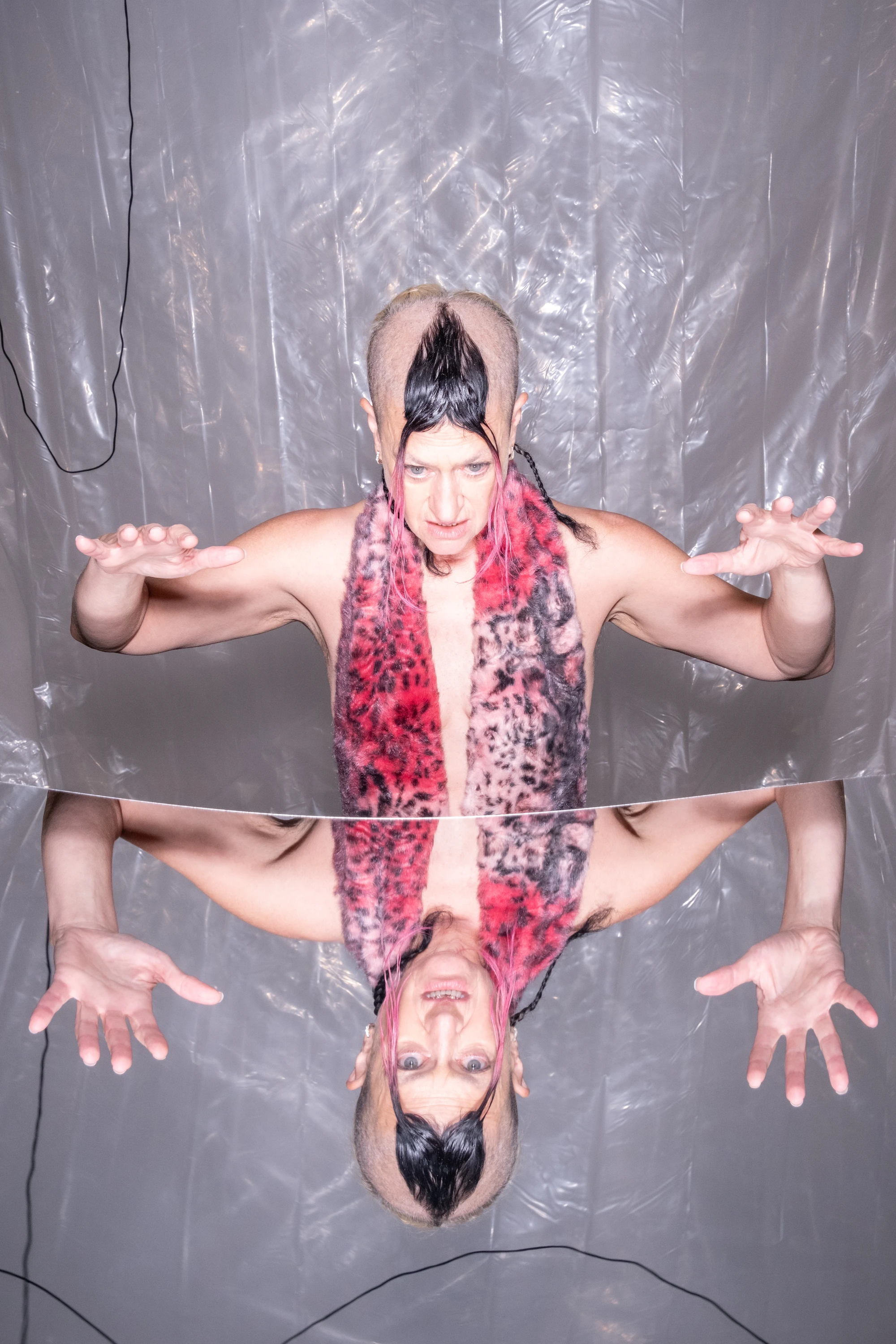 A mirrored portrait of Peaches with arms extended.