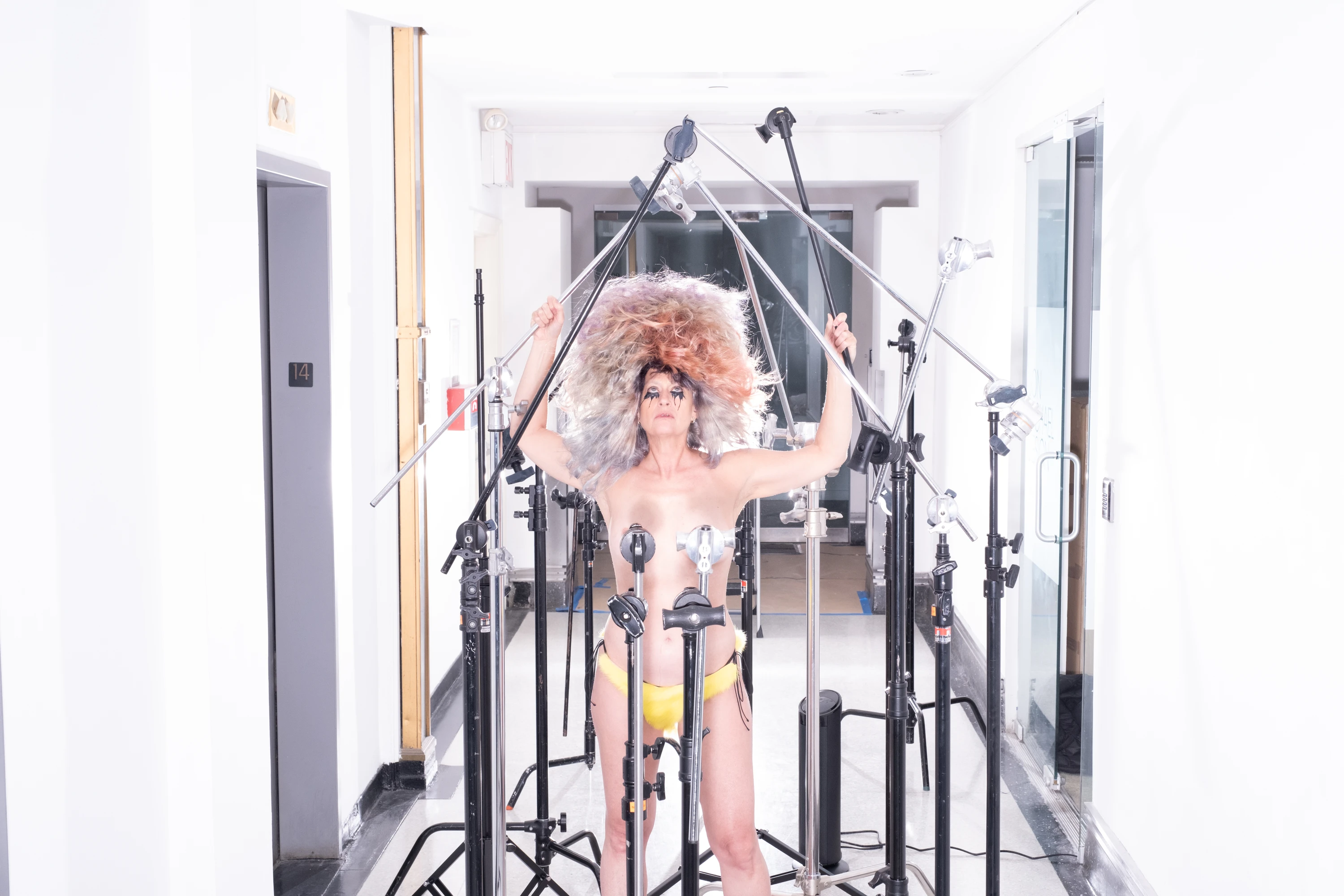 Peaches raising her arms among studio stands.