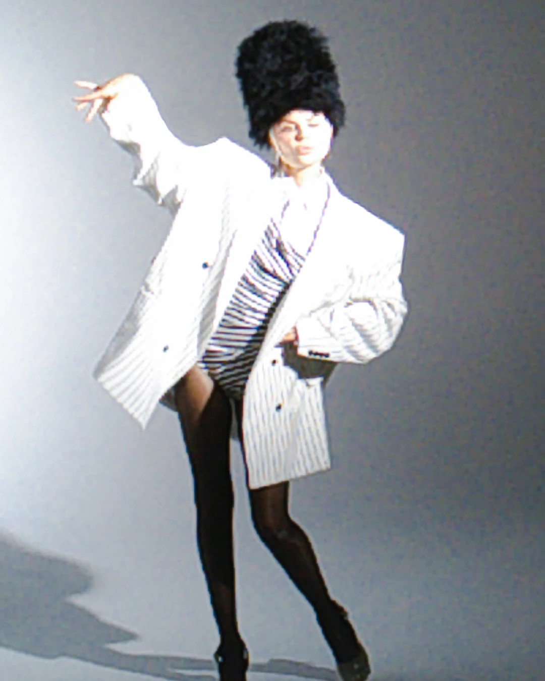 Lisa Rinna posing in a white jacket and tall dark hat.