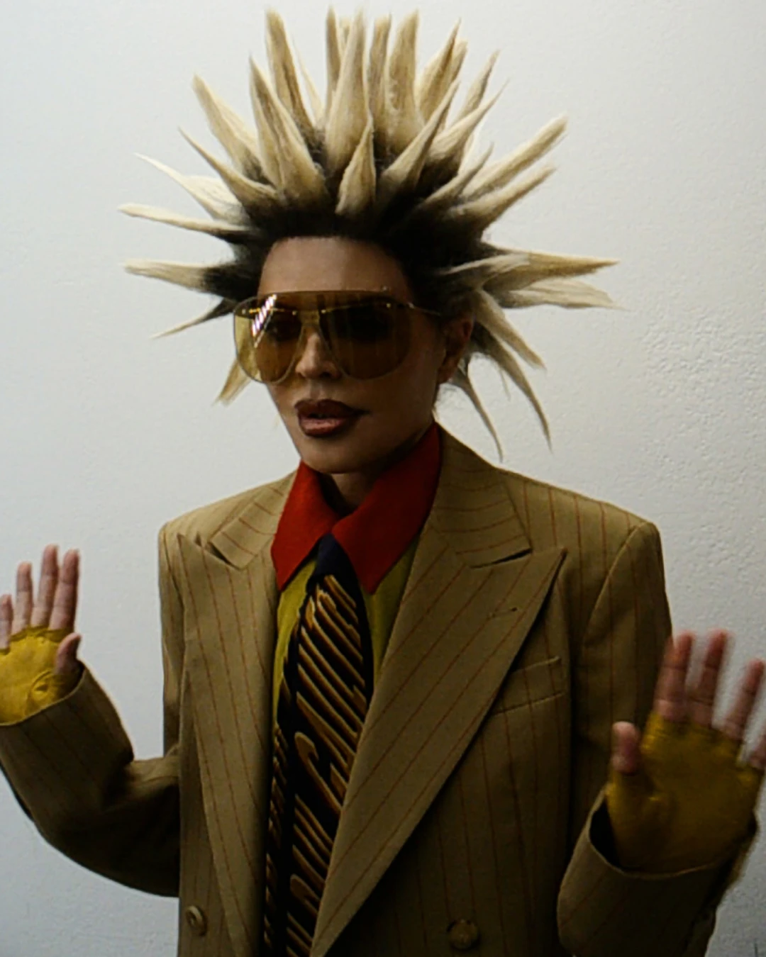 Lisa Rinna raising both hands in a suit and sunglasses.