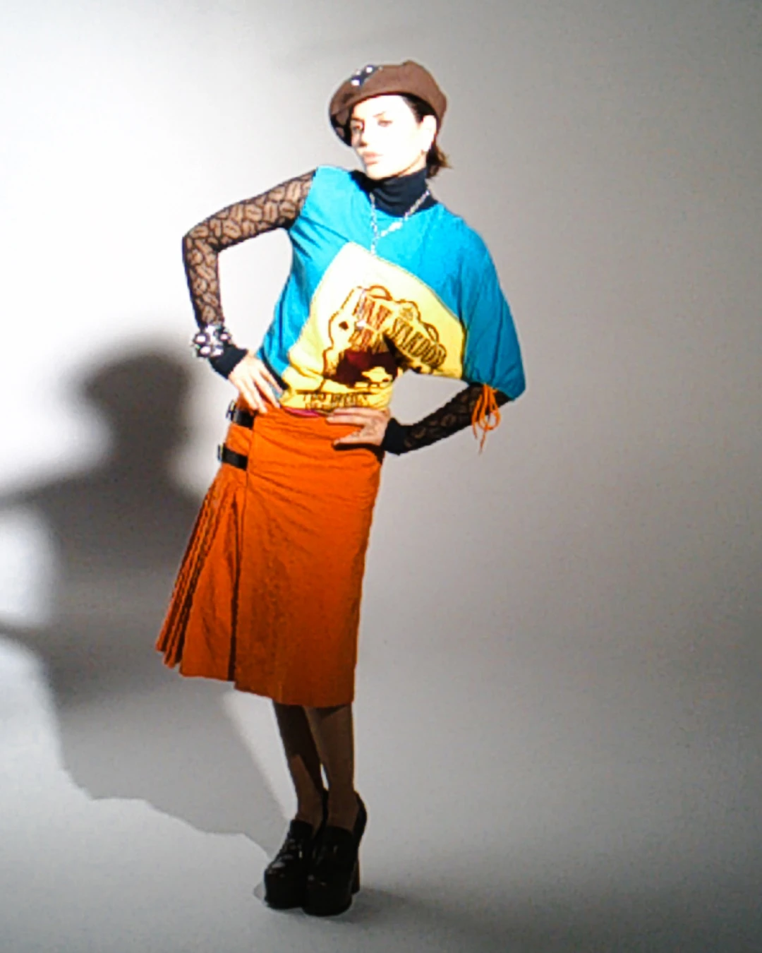 Lisa Rinna posing in a colorful top and orange skirt.
