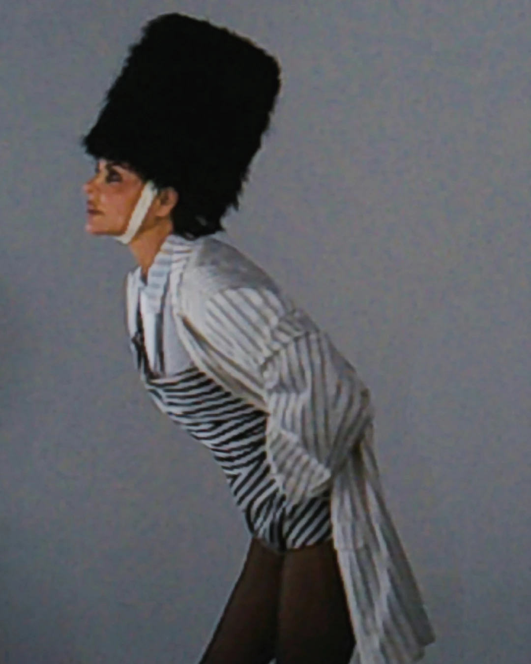 Lisa Rinna leaning forward in a striped jacket and tall hat.