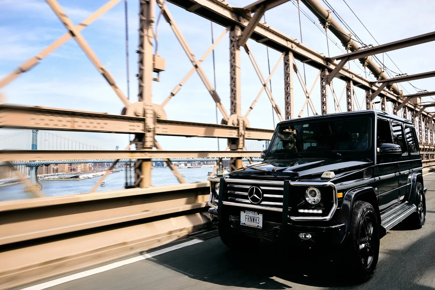 A black Mercedes-Benz SUV traveling across a steel bridge.