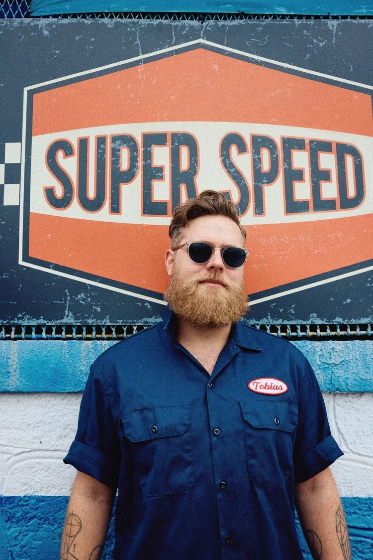 Tobias van Schneider standing in front of a Super Speed sign.