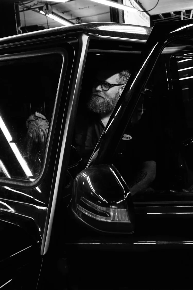 Black-and-white portrait of Tobias van Schneider inside a vehicle.