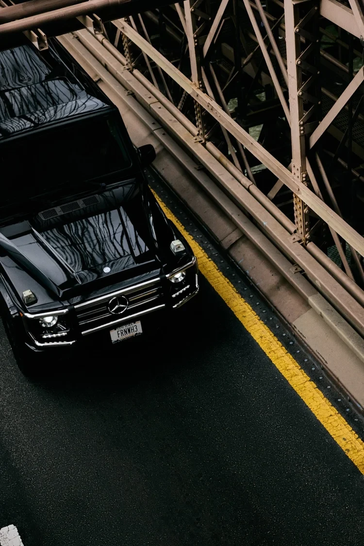 An overhead view of a black SUV on a steel bridge.