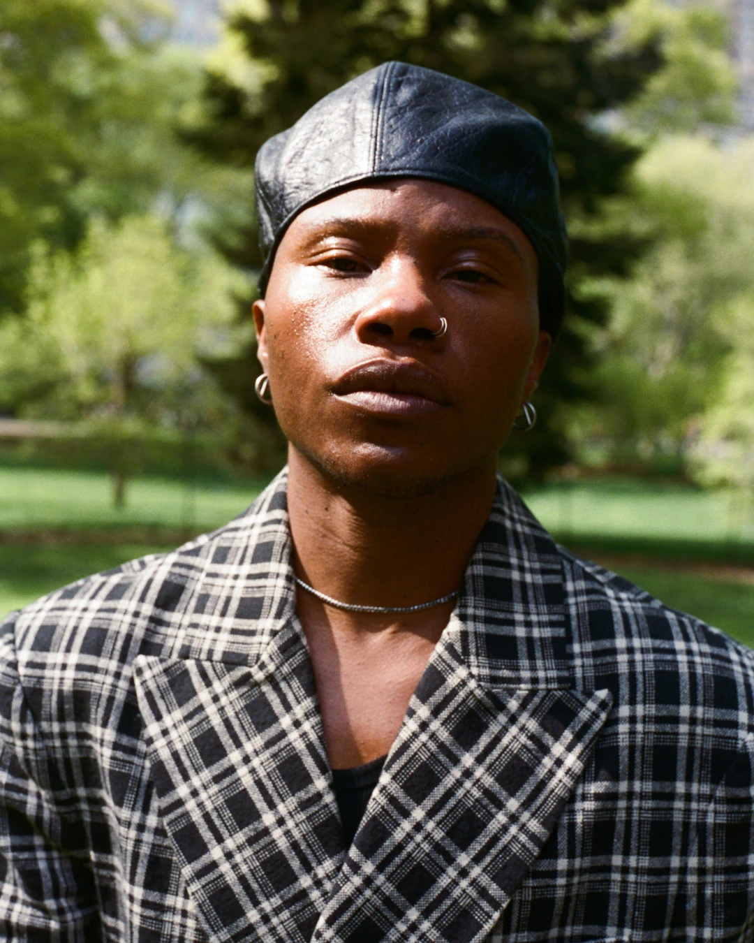 Close portrait of TYGAPAW wearing a plaid jacket and cap.