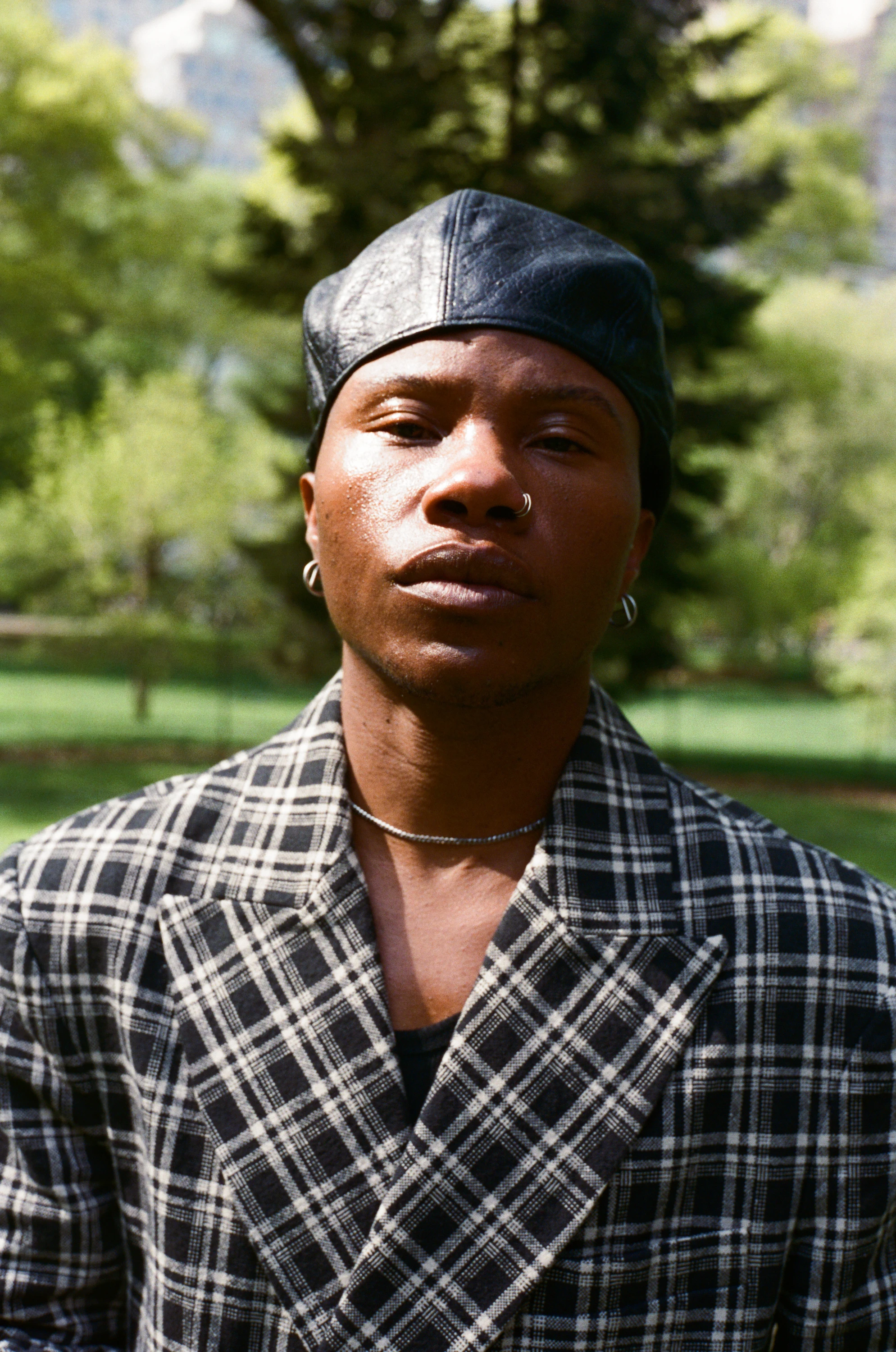 TYGAPAW wearing a plaid jacket and dark cap outdoors.