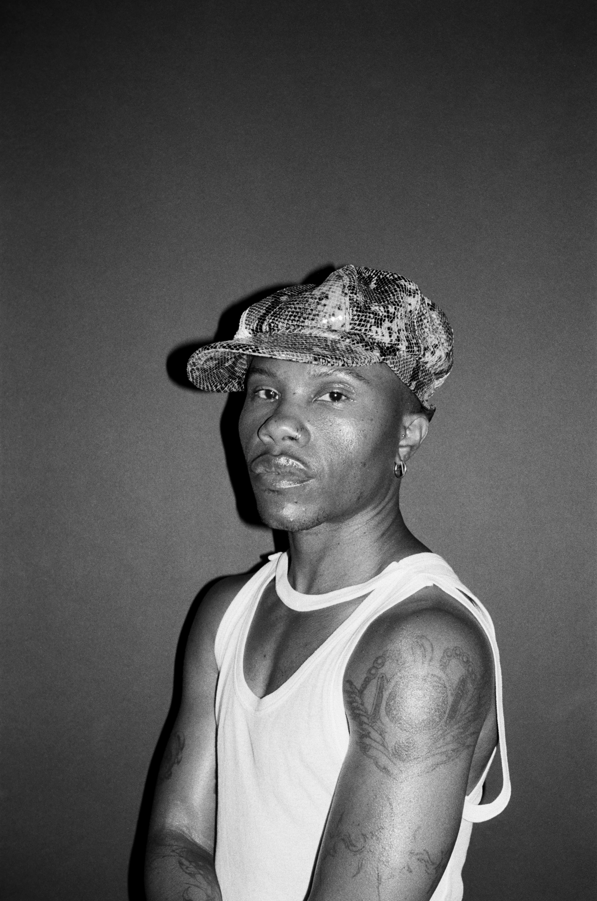 Black-and-white portrait of TYGAPAW wearing a cap and sleeveless top.