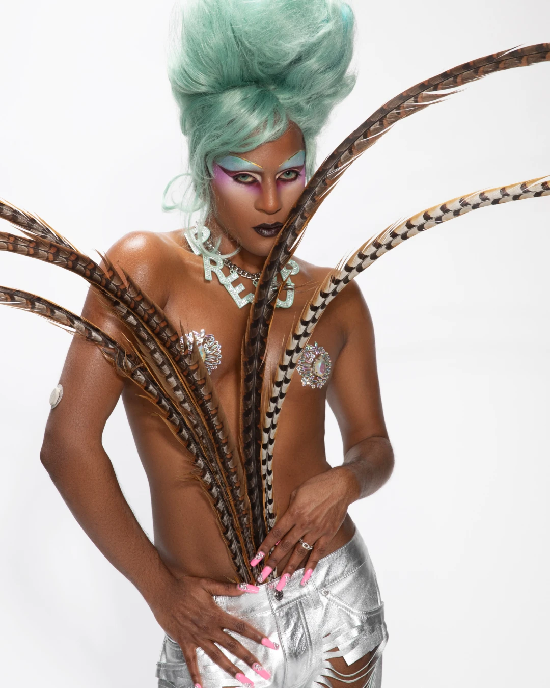 Richie Shazam in a sculptural feathered outfit with green hair.