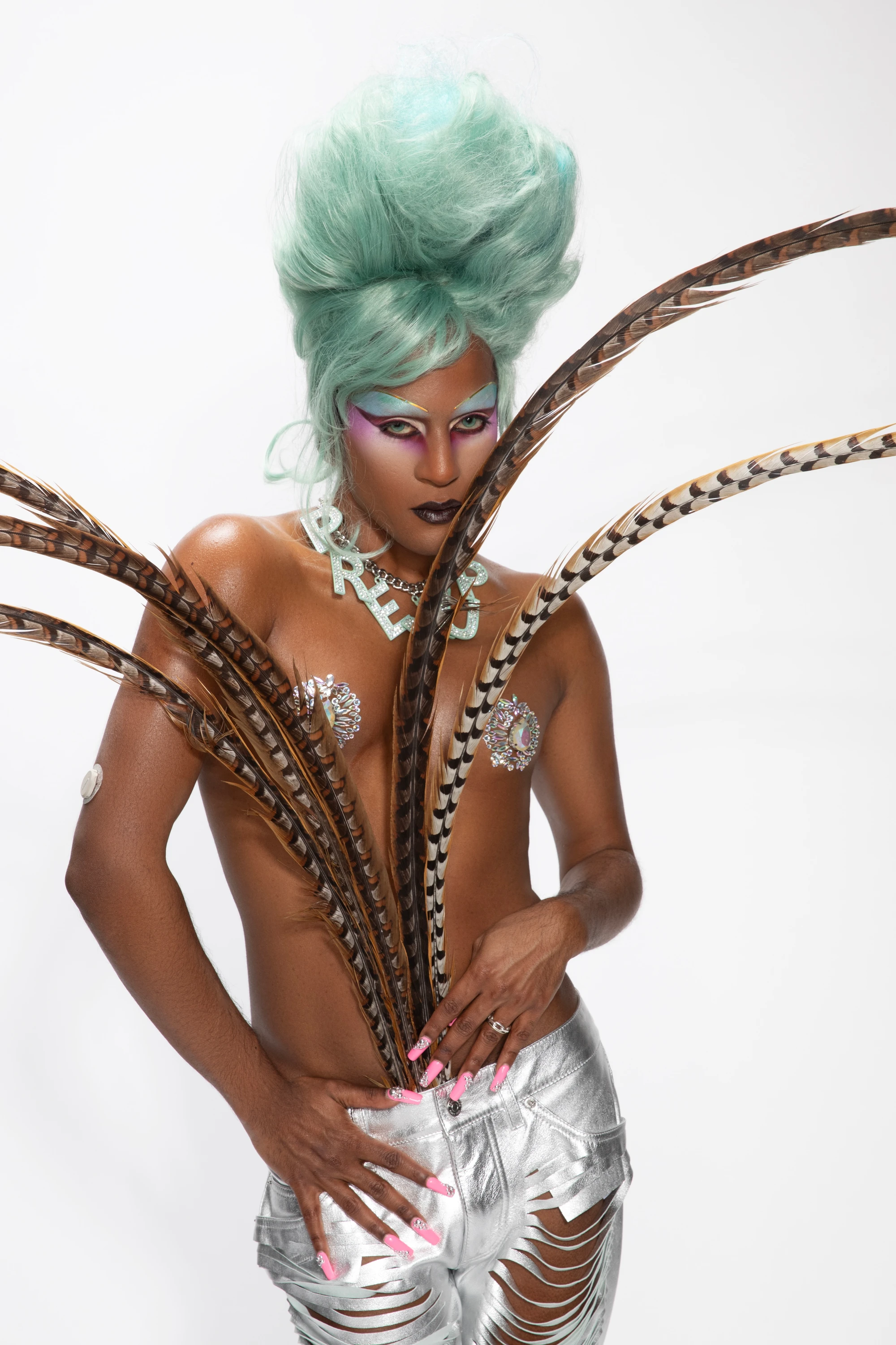 Richie Shazam wearing a sculptural feathered outfit with green hair.