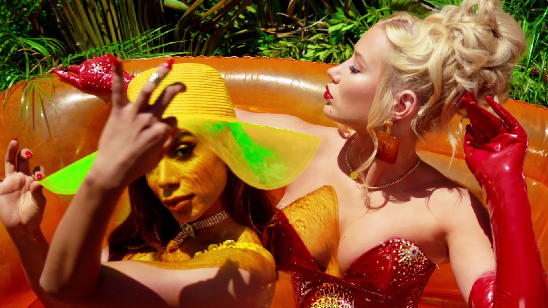 Iggy Azalea reclining beside another performer on colorful inflatables.