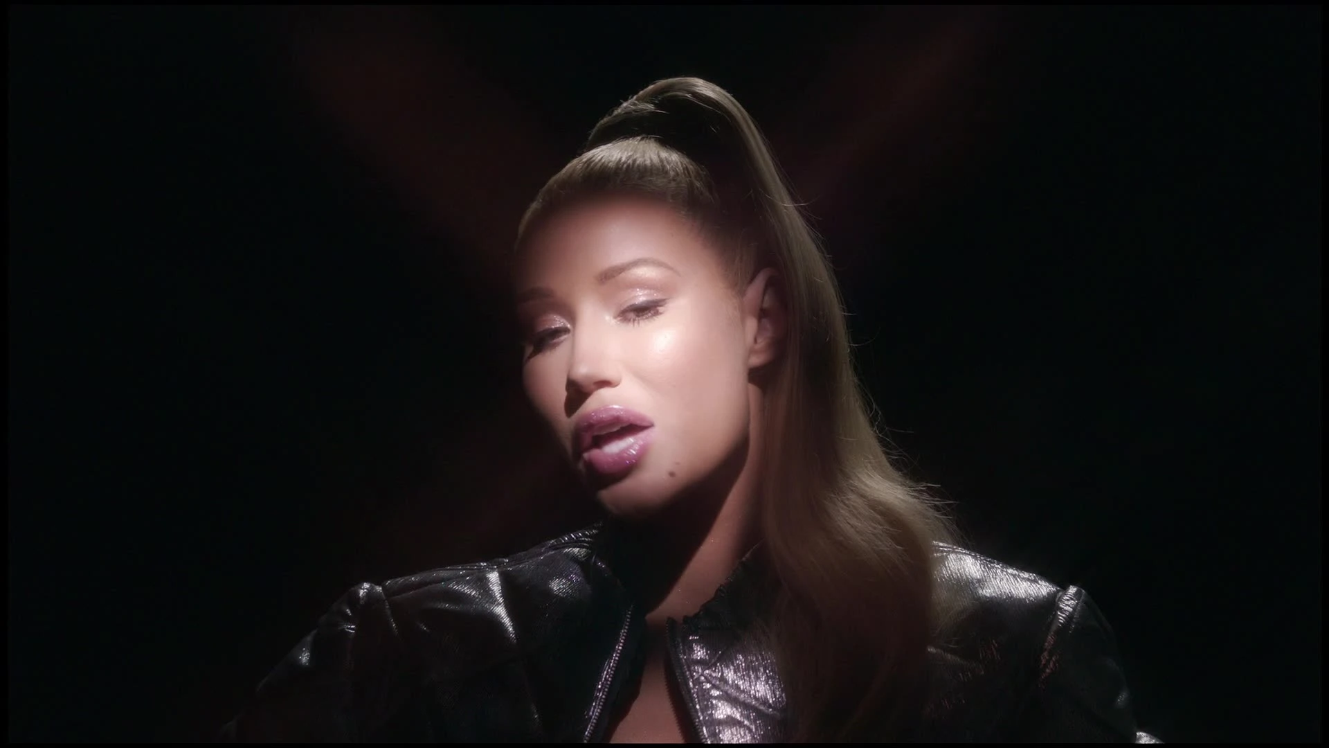 A performer in a dark jacket against a black background.