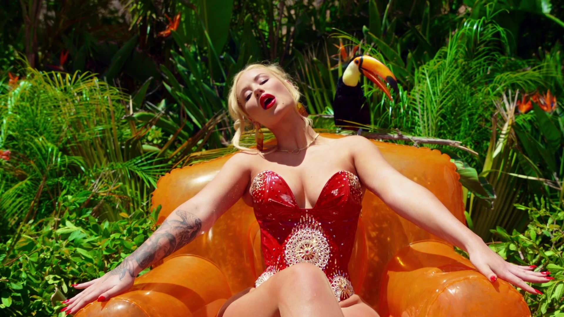 Iggy Azalea reclining on an orange inflatable.
