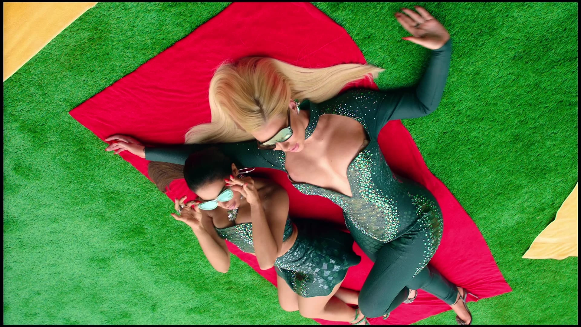 An overhead view of two performers reclining on a red mat.