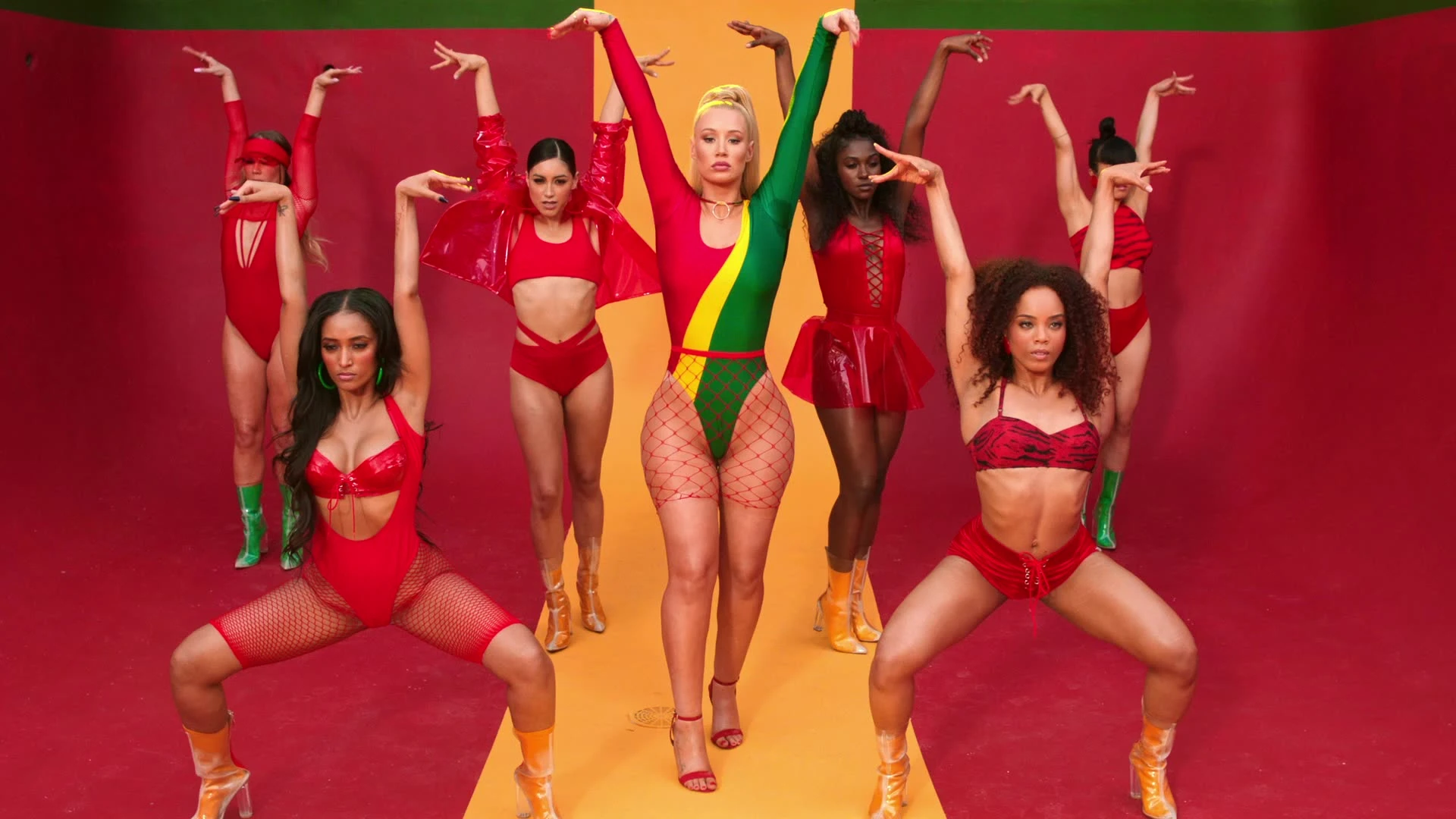 Iggy Azalea raising her arms with dancers behind her.