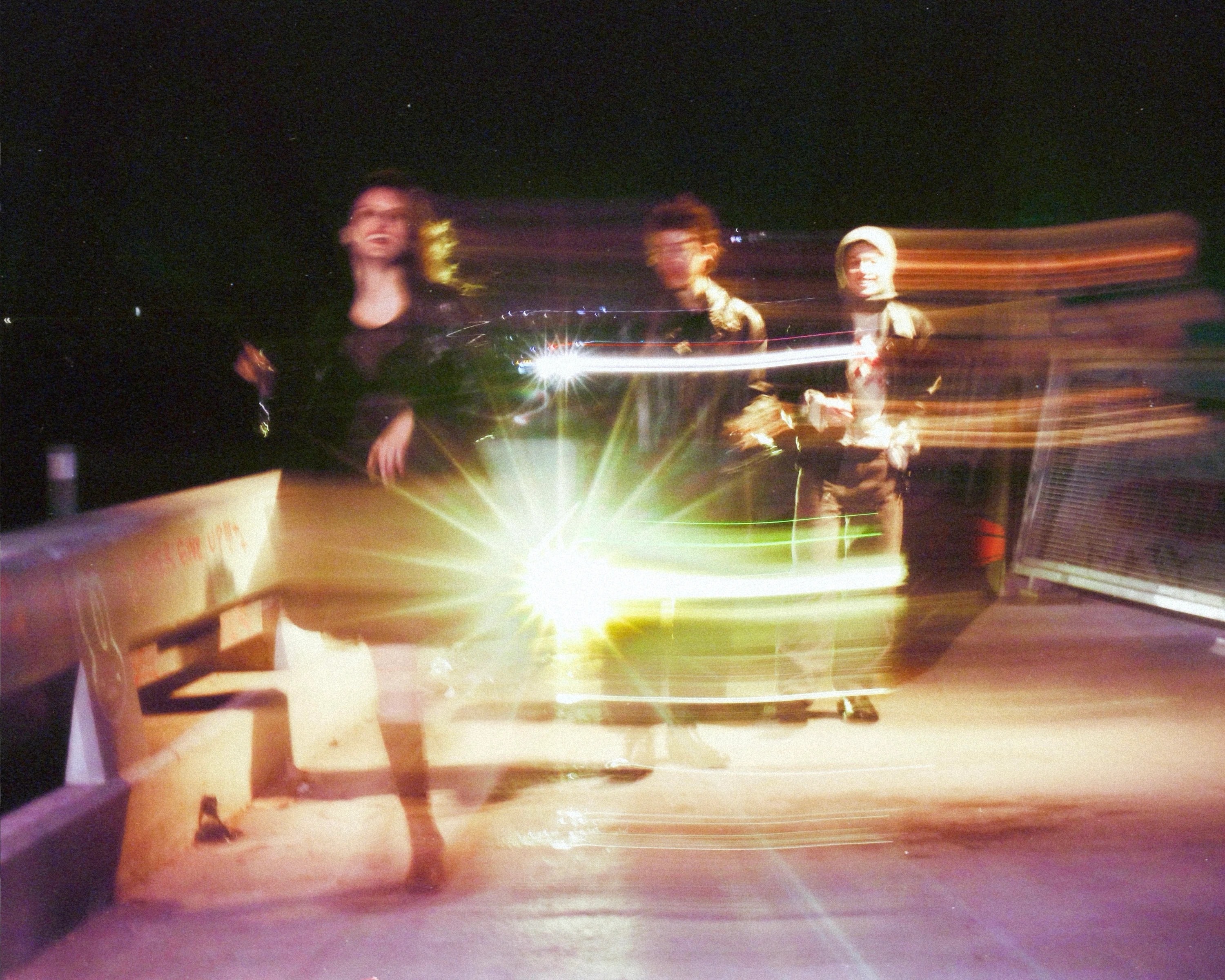 MUNA performing amid streaks of colored light.