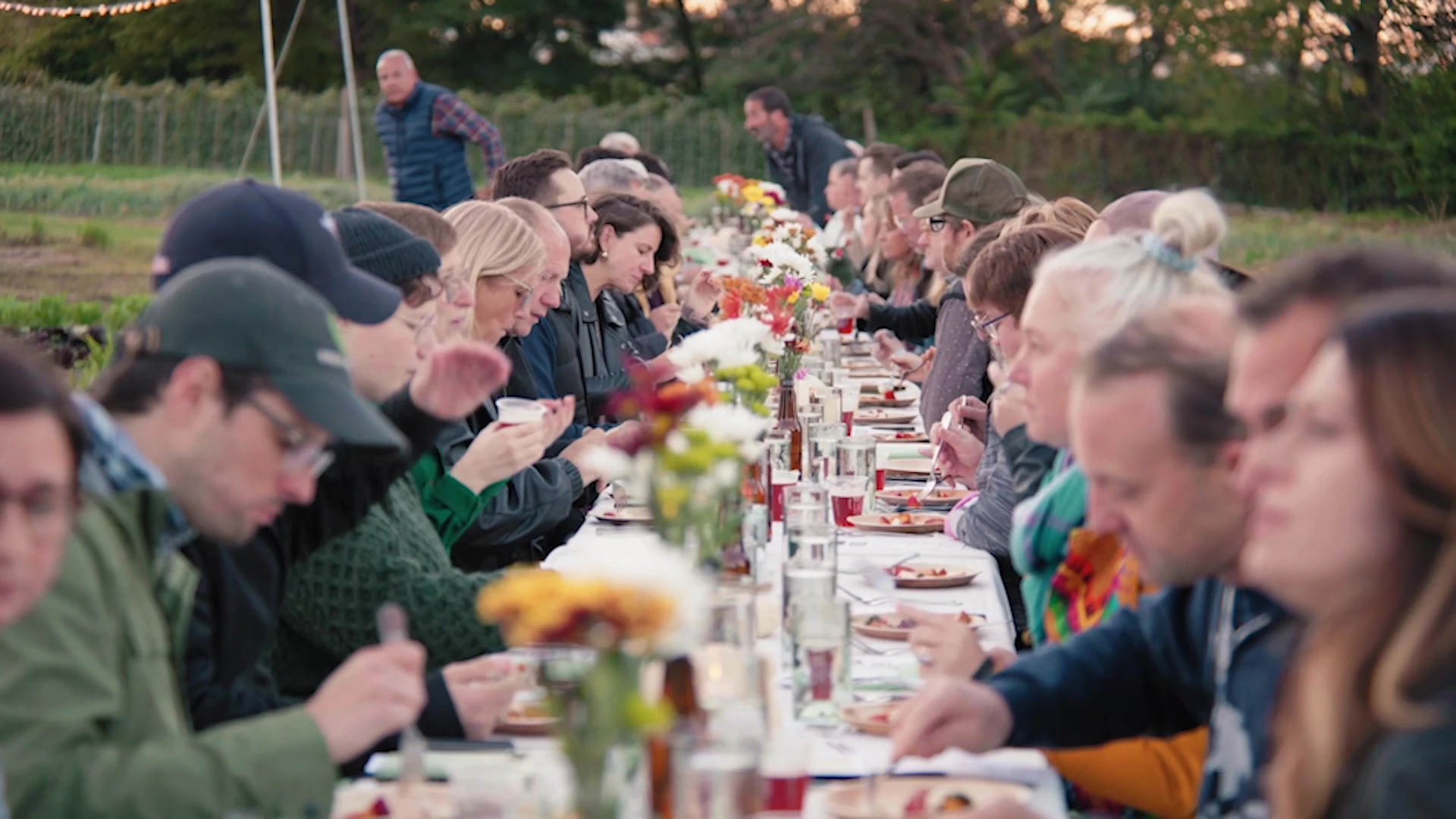 People sharing a meal at a long outdoor table.