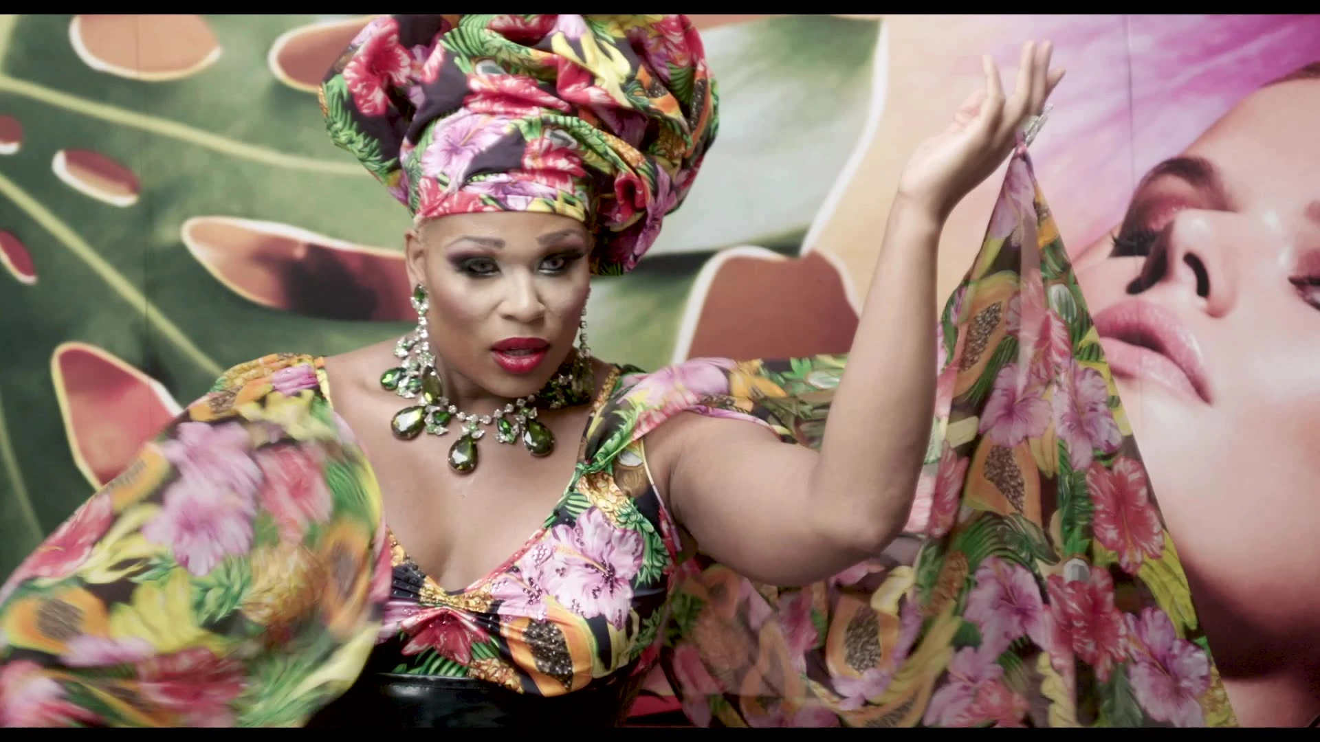 A performer posing in a floral outfit and headwrap.