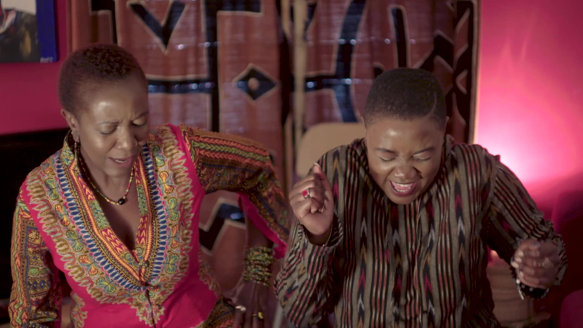 Two people laughing together indoors.