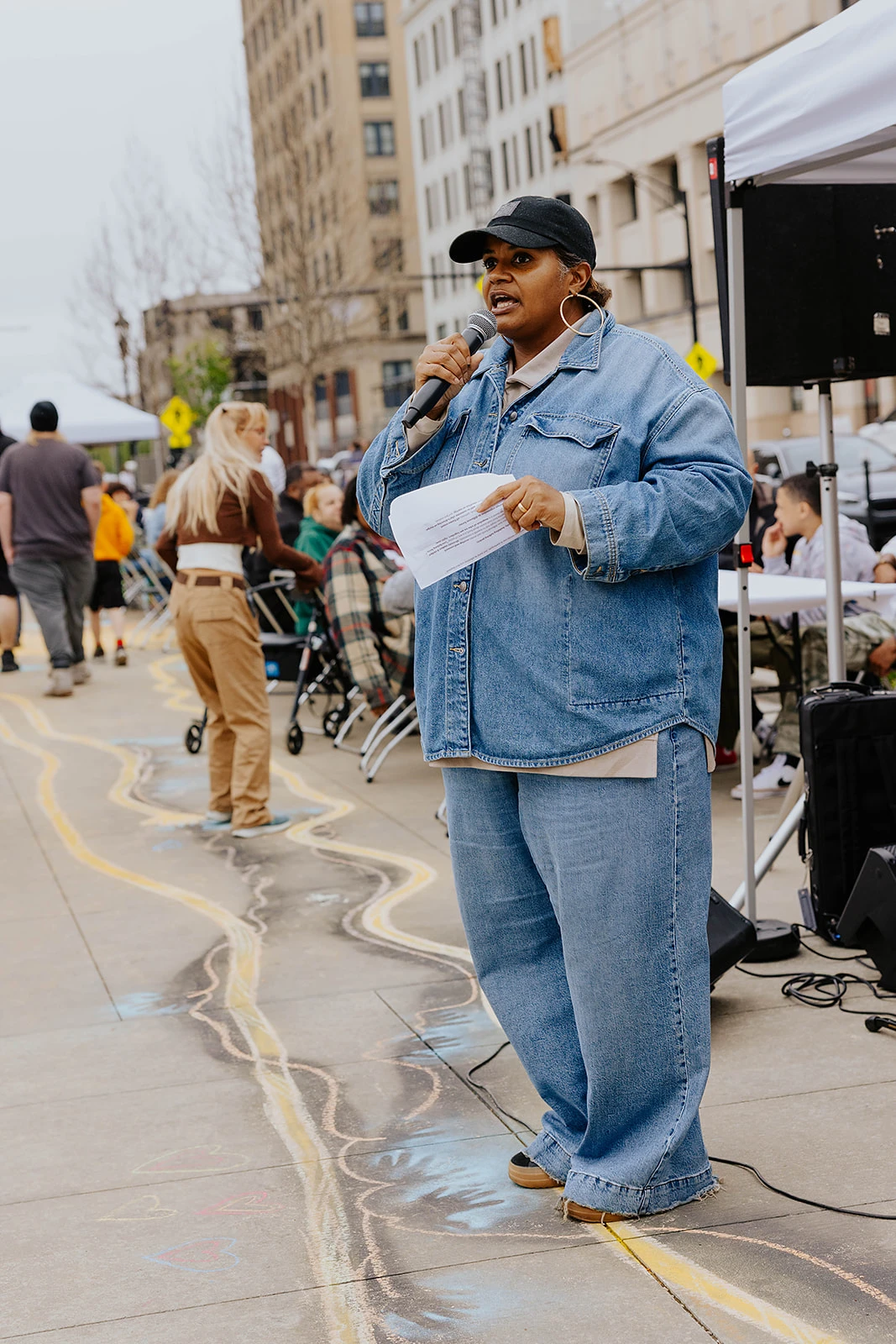 A speaker holding a microphone on a downtown sidewalk.