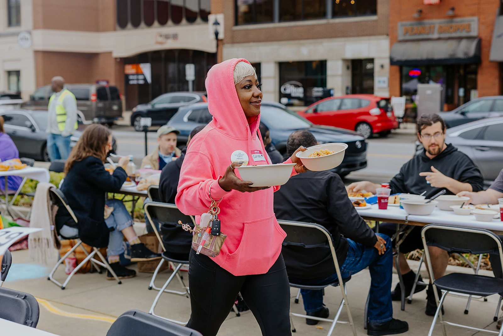 A participant carrying plates between outdoor tables.