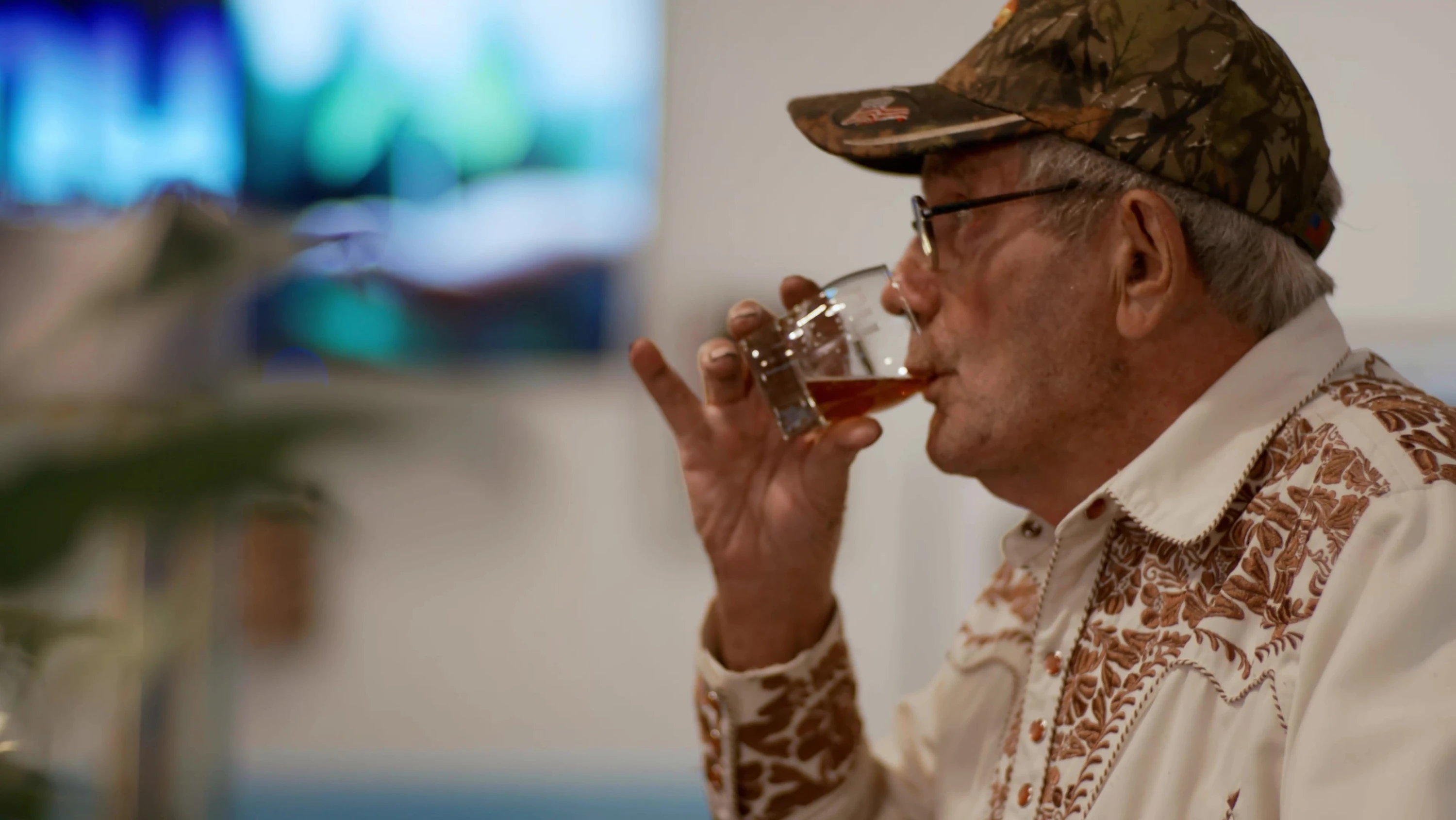 A person tasting beer from a small glass.